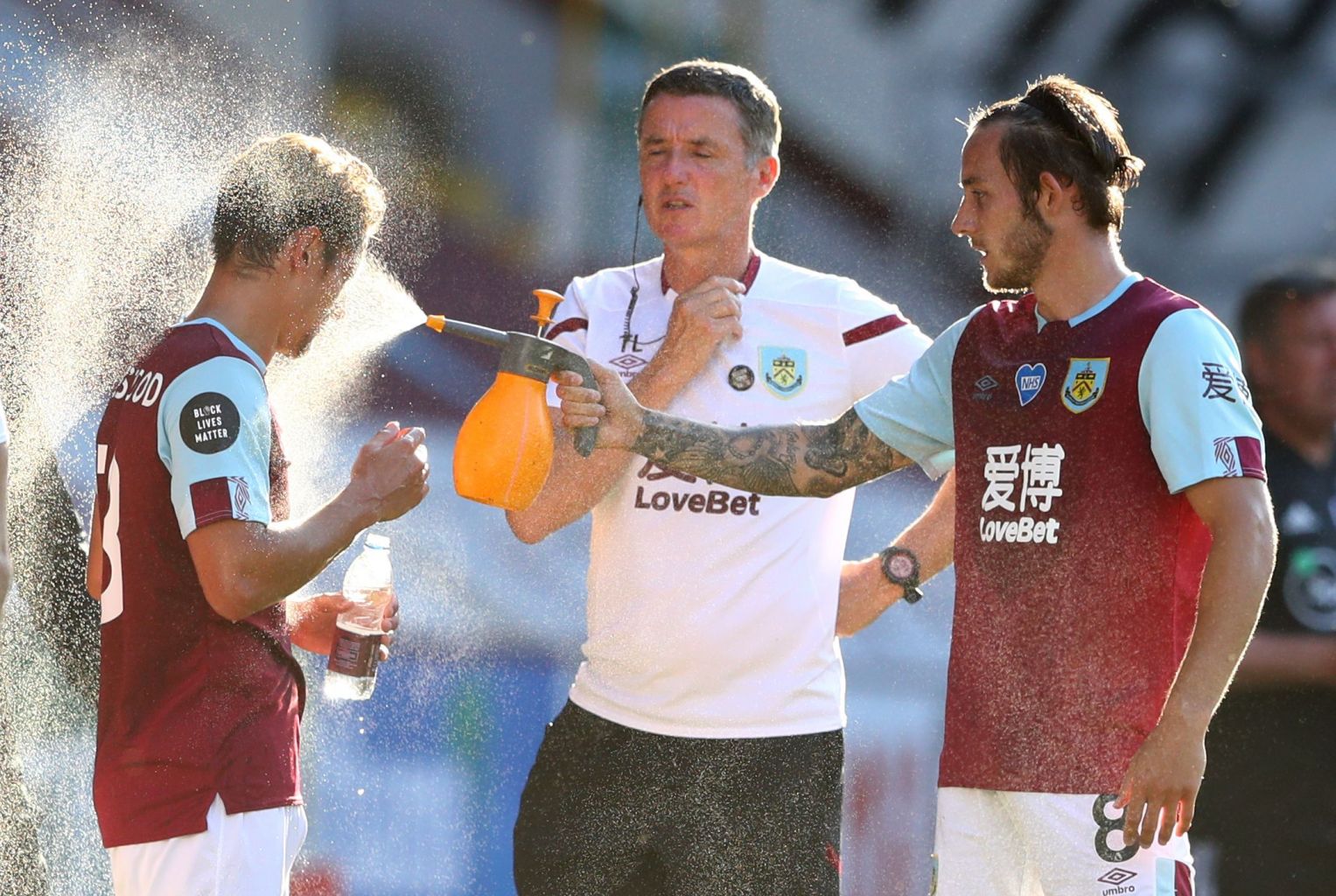 Burnley’s Josh Brownhill spraying water on Ashley Westwood during a drinks break, one of the protocols for the Premier League restart. 