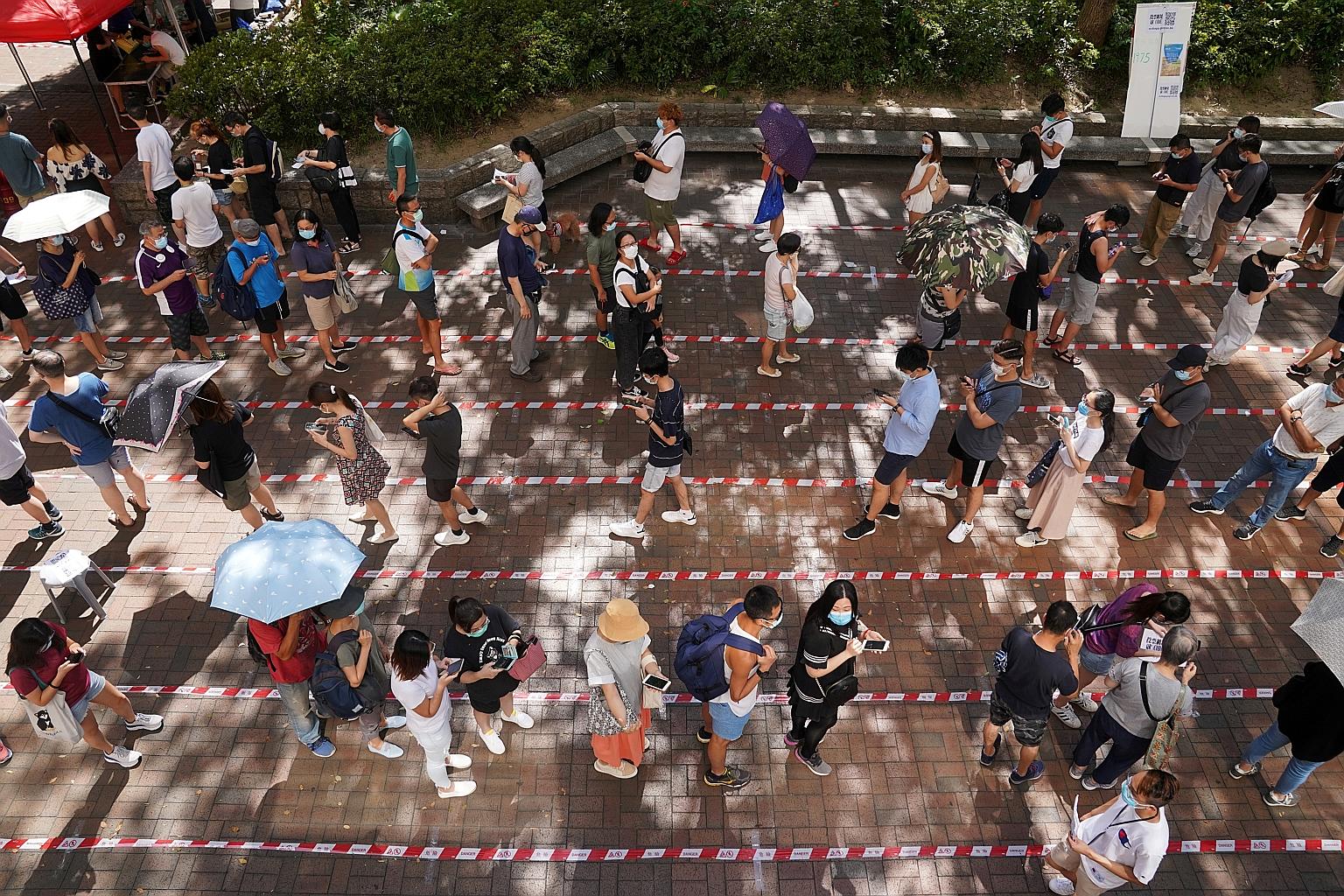 People lining up to vote in the unofficial primary election in Hong Kong on Sunday. The Hong Kong Public Opinion Research Institute said paper ballots for Hong Kong Island had been counted and it was tallying votes for other districts. PHOTO: REUTERS