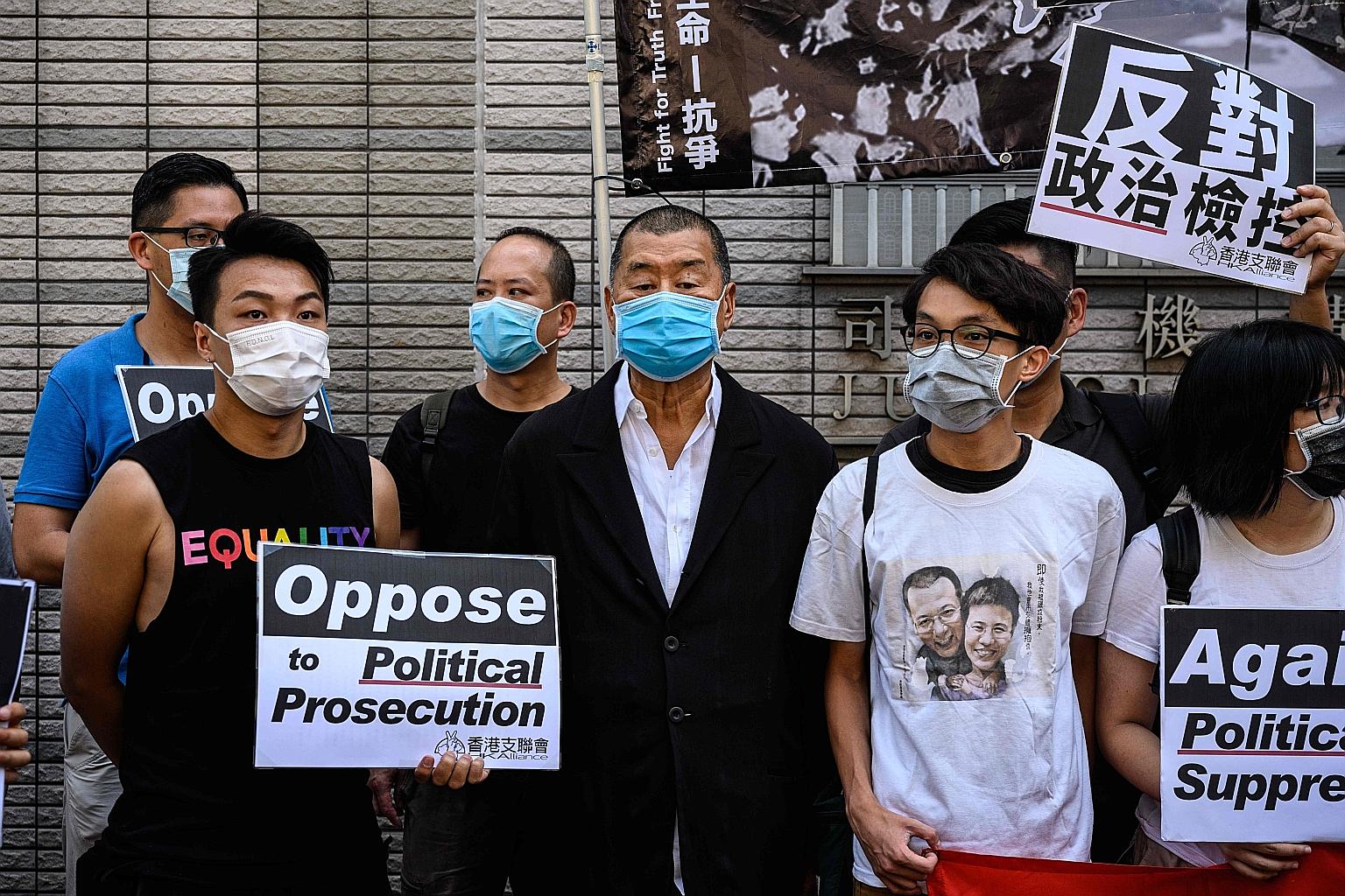 Media tycoon Jimmy Lai (centre), with supporters and other democracy activists, gathering in public before attending a mention at the West Kowloon Magistrates Court in Hong Kong yesterday. He was among 13 prominent activists charged with holding an u