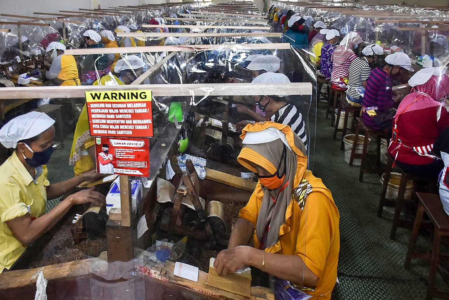 Workers, separated by plastic sheets at their workstations, rolling tobacco at a factory in Malang, East Java, last Saturday.
