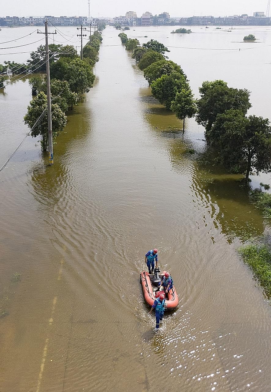 Rescue workers wading through flood waters with an inflatable boat yesterday to reach people trapped in their homes in the township of Sanjiao, in Yongxiu county, south-eastern China's Jiangxi province. Poyang Lake, which is China's largest freshwate
