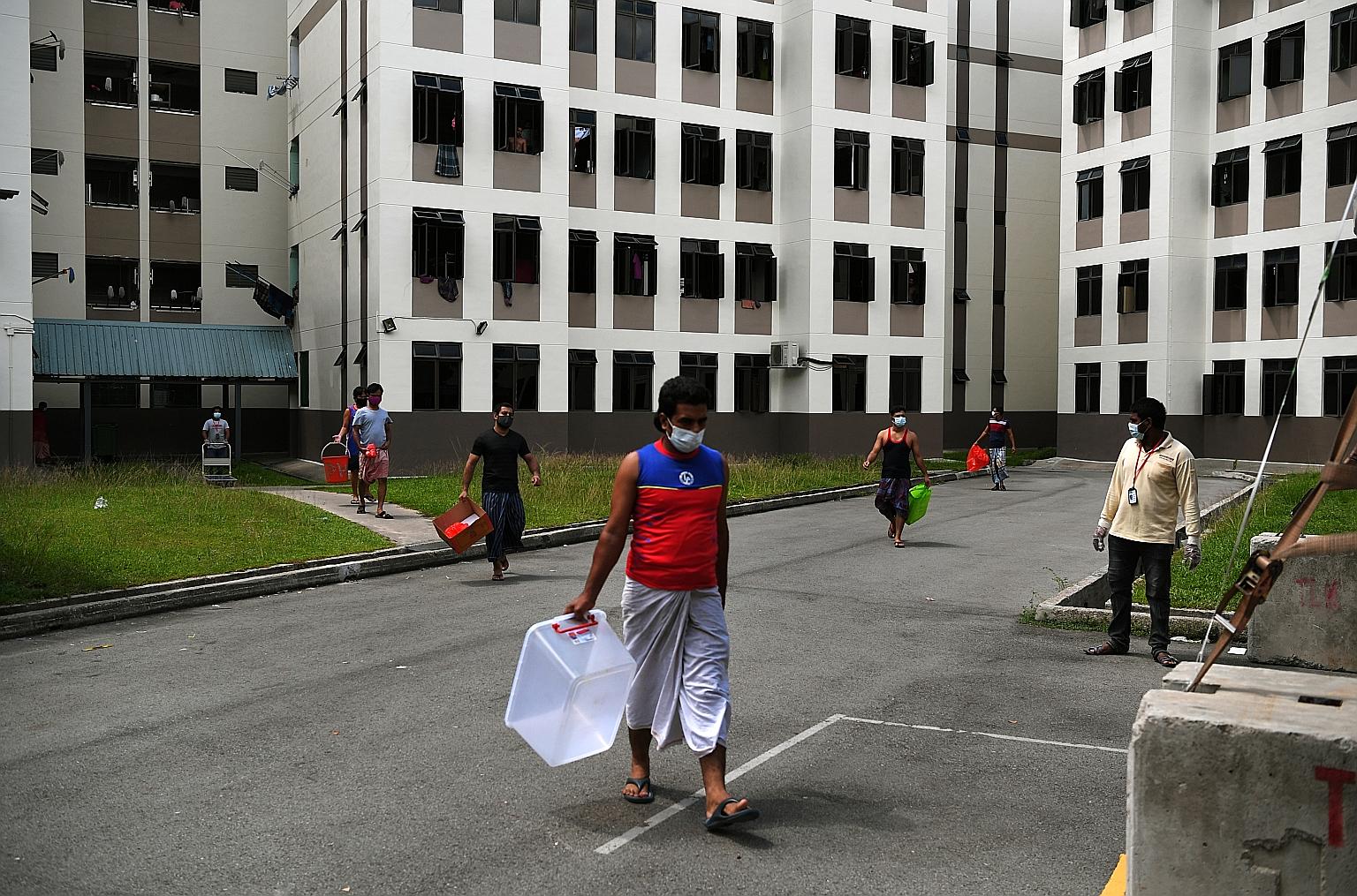 Residents of Tampines Dormitory heading to the food collection centre to pick up their lunch early last month. Many workers staying in dormitories who are infected are likely to show no symptoms, allowing the virus to continue spreading and making th