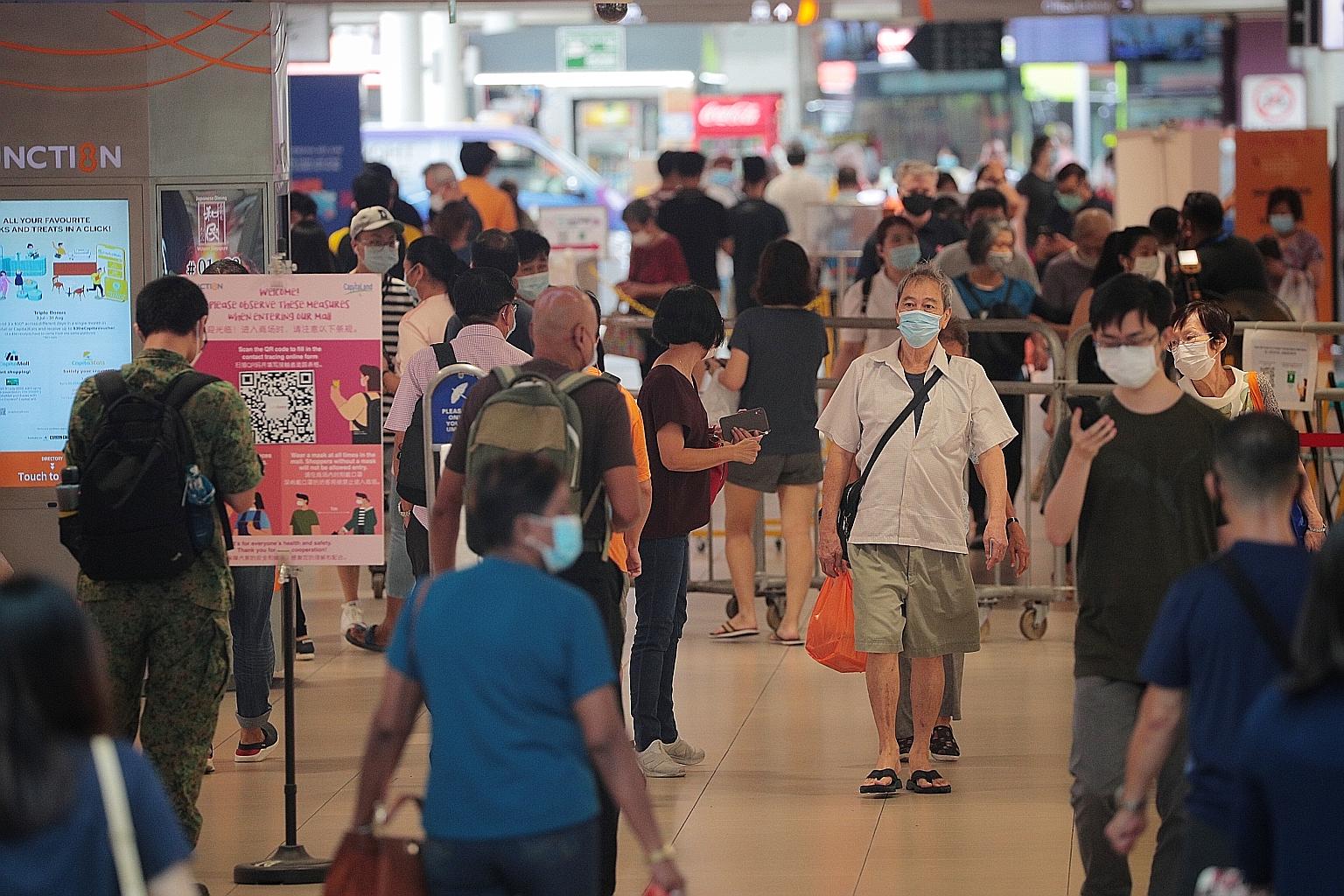 Pedestrians at the entrance of Junction 8 mall in Bishan yesterday. MOH said the higher number of cases yesterday was due to the clearing of a backlog of samples.