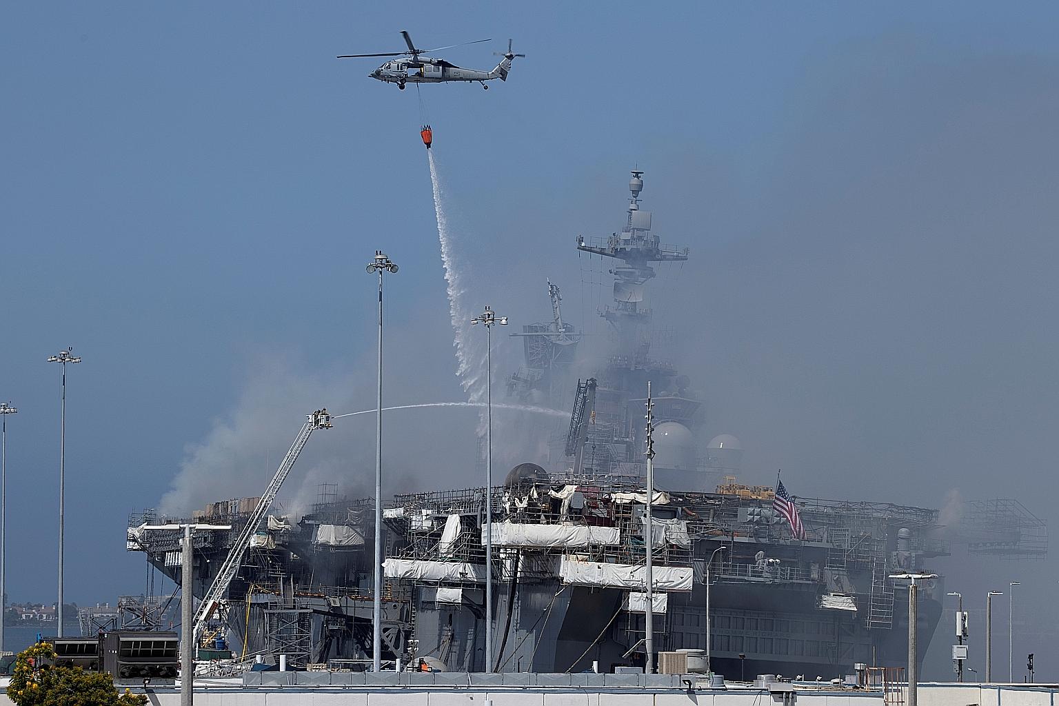 US Navy helicopters and city firefighters fighting the spreading fire on the amphibious assault ship USS Bonhomme Richard at US Naval Base San Diego on Monday. The warship caught fire on Sunday. PHOTO: REUTERS