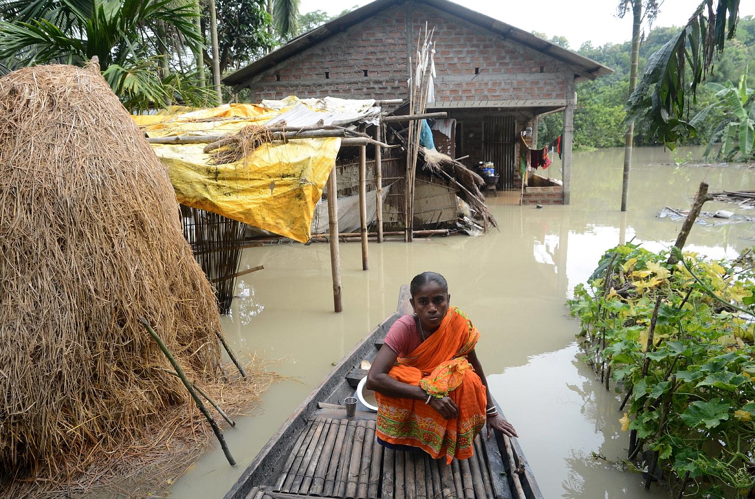 A woman in front of her partially submerged house in Chandrapur, in the Kamrup district of Assam, on Wednesday. Monsoon floods have killed at least 10 people and injured more than 70 in the states of Assam, Bihar and Jharkhand, where heavy rain has s