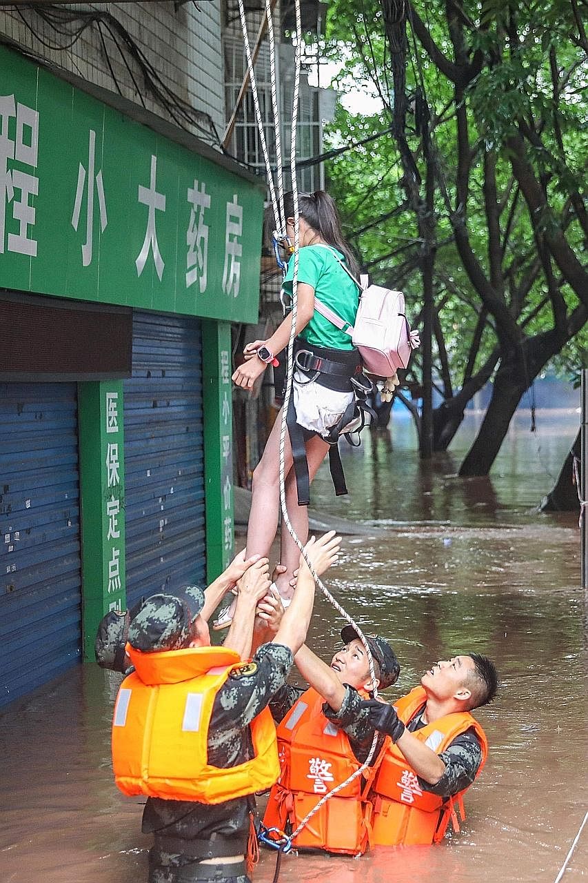 Paramilitary police officers helping to evacuate a resident from her house in a flooded area in China's south-western Chongqing city. PHOTO: AGENCE FRANCE-PRESSE