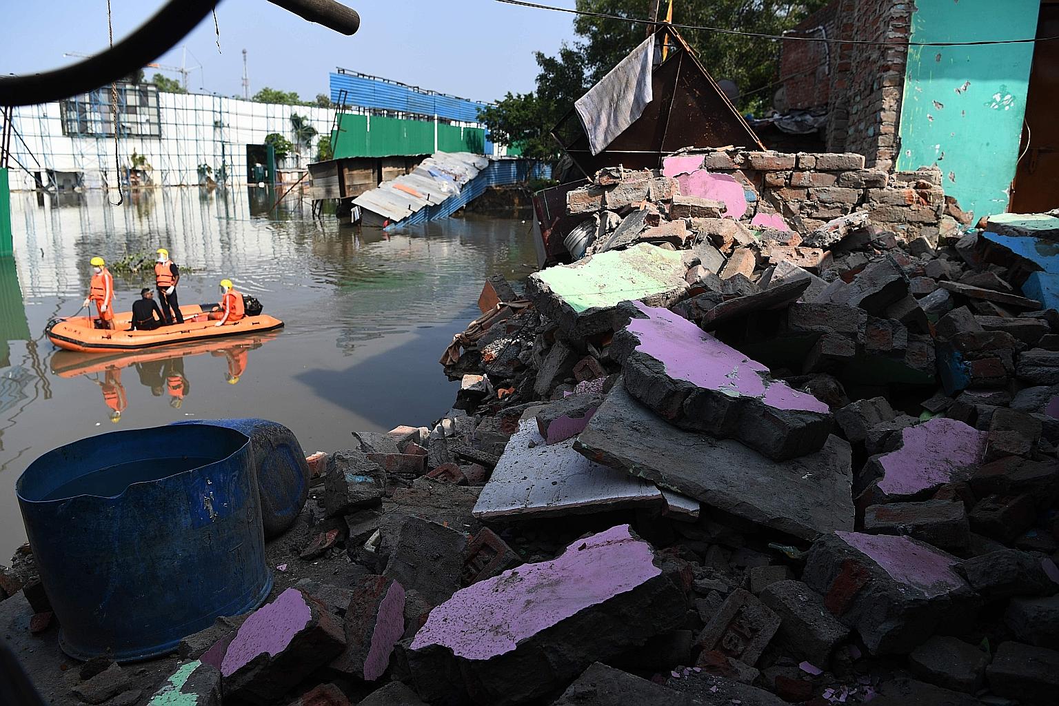 Indian National Disaster Response Force personnel surveying an area where some shanty houses collapsed into a canal due to heavy rain in New Delhi yesterday. PHOTO: AGENCE FRANCE-PRESSE