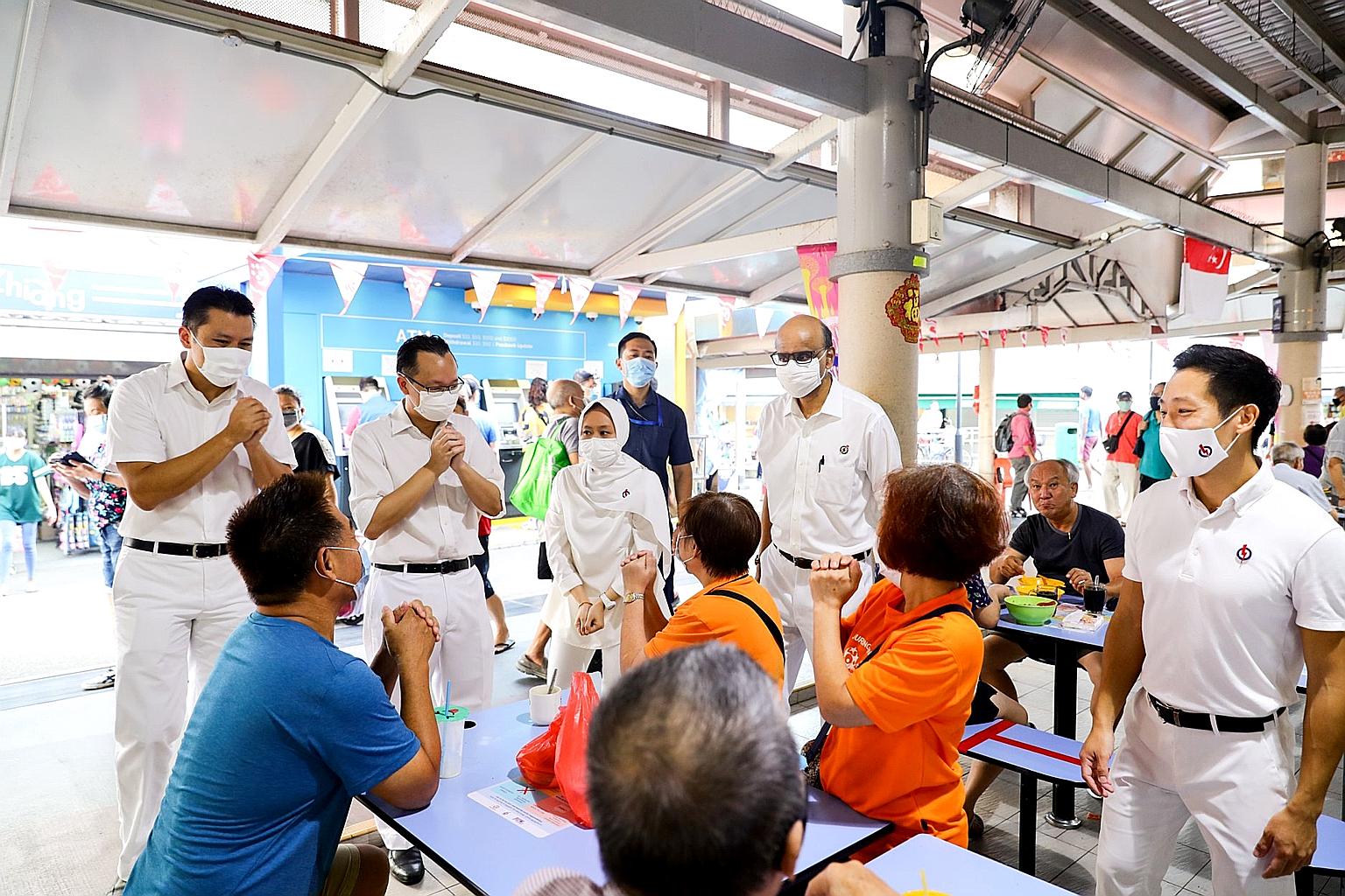 Senior Minister Tharman Shanmugaratnam (standing, second from right) with fellow Jurong GRC MPs (from left) Shawn Huang, Tan Wu Meng, Rahayu Mahzam and Xie Yao Quan speaking to patrons during a visit to a hawker centre in the constituency to thank re