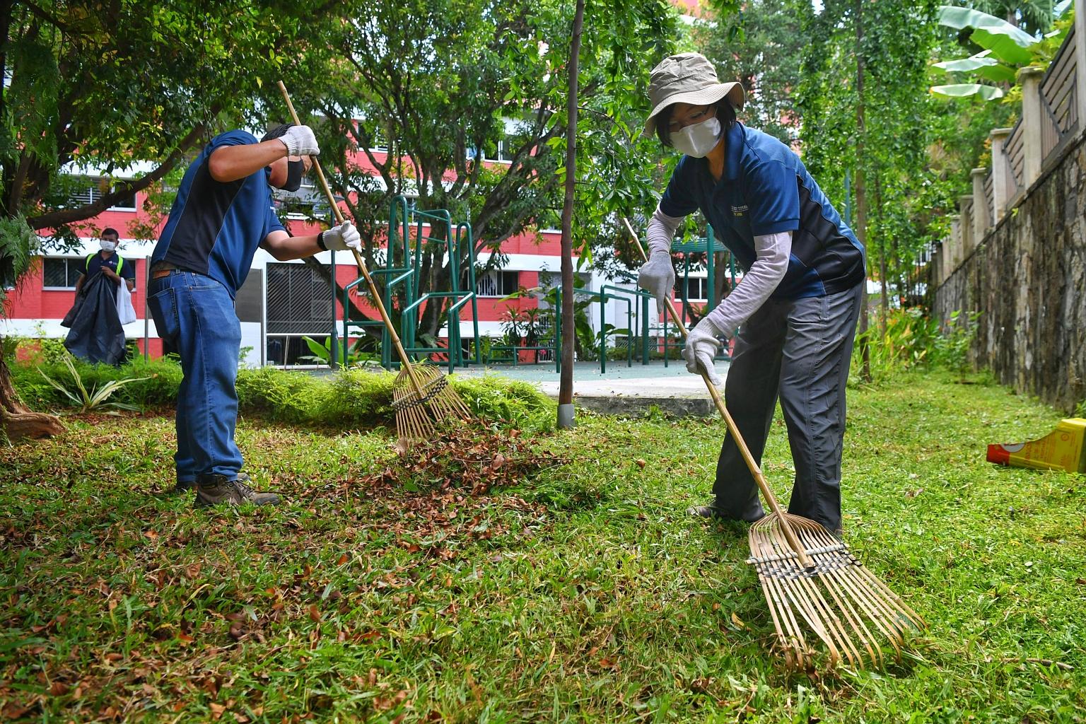 Senior Minister of State Sim Ann (right), who is an MP for Holland-Bukit Timah GRC, helping to clear the grass after it was cut by migrant workers who volunteered their time yesterday. Ms Sim said: "I was very touched... that they are willing to come