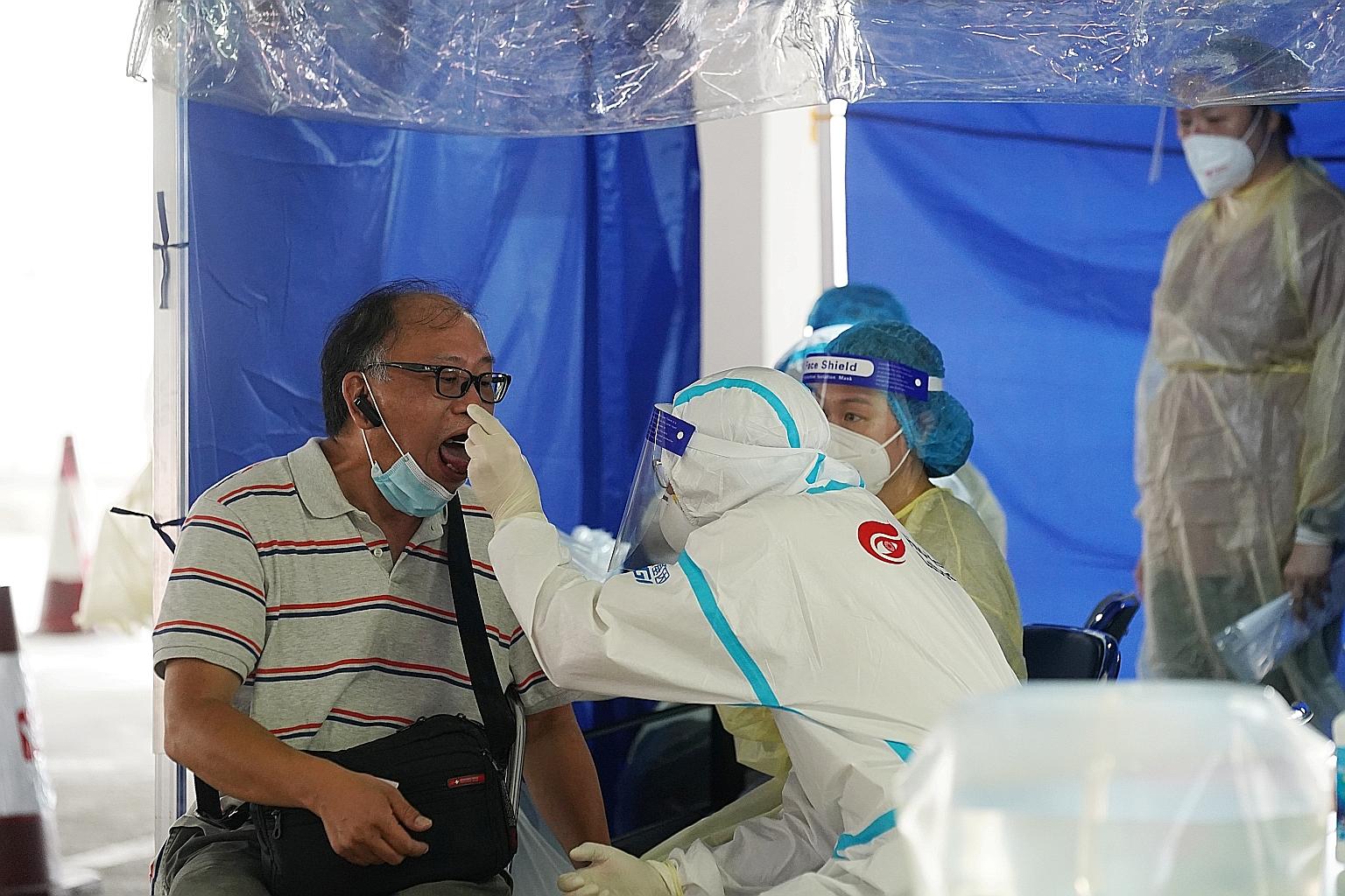 A medical worker collecting a sample to be tested for Covid-19, at a specimen collection point for taxi drivers in a carpark in Hong Kong yesterday. Covid-19 testing facilities in the city are swamped, with many private hospitals reportedly fully boo