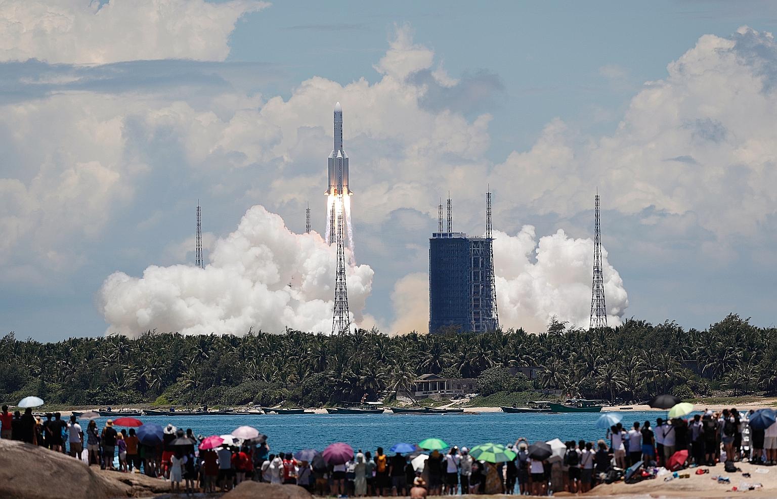 A crowd of onlookers watching from a beach as the Long March 5 Y-4 rocket, carrying the unmanned Tianwen-1 probe, blasted off on its Mars mission yesterday. This photo from China Daily shows the rocket launch at the Wenchang Space Launch Centre on Ch