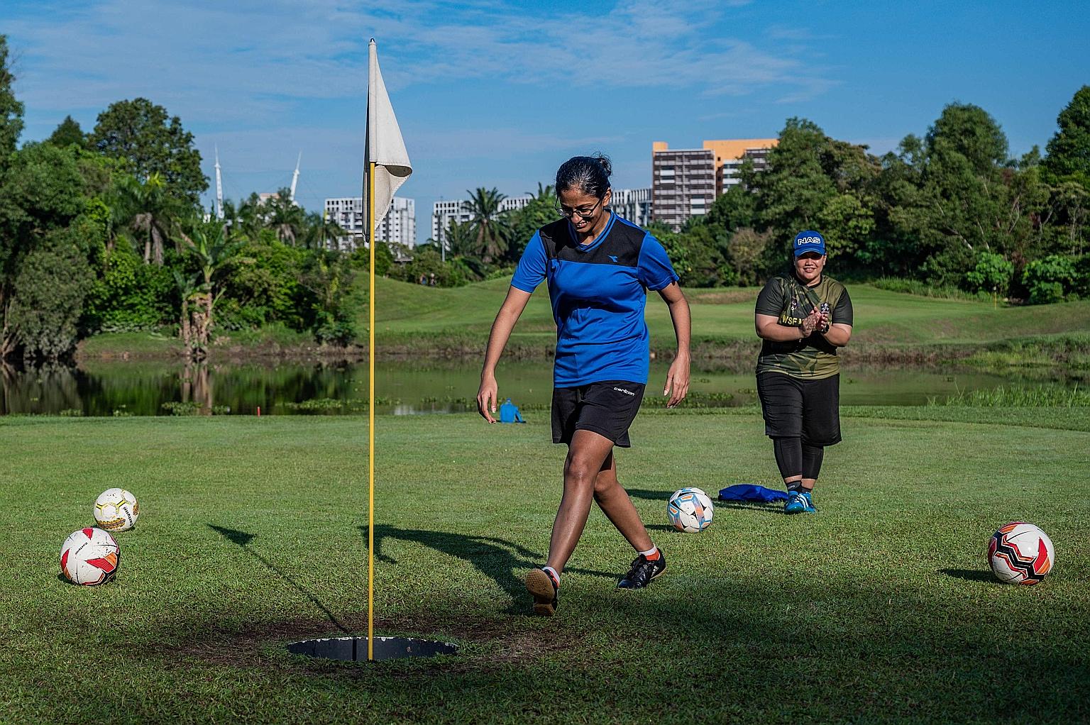 Sabrina Joan smiling after her successful "foot putt" on a footgolf course in Shah Alam while Jamiatul Akmal Abdul Jabar applauds. The novel sport footgolf is giving golf courses in Malaysia a new source of revenue as young people lose interest in pl