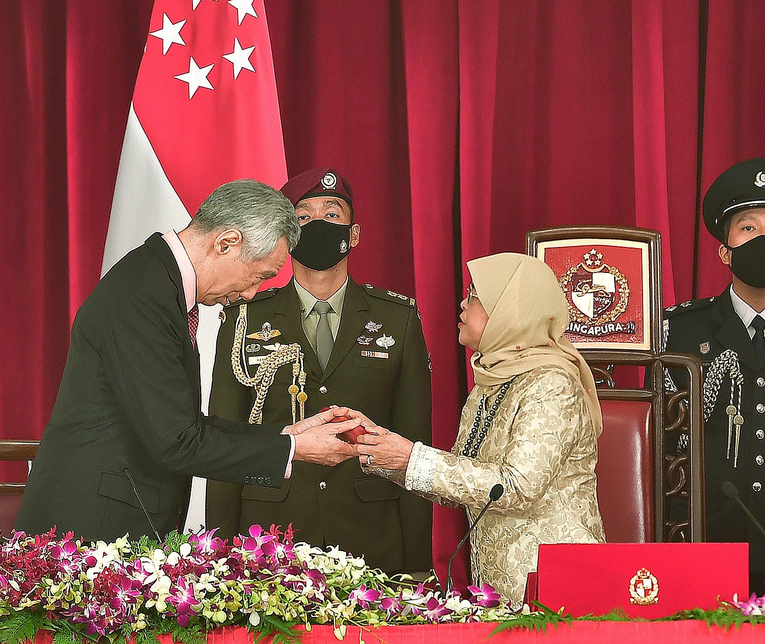Prime Minister Lee Hsien Loong receiving the instrument of appointment from President Halimah Yacob at the Istana yesterday, during the swearing-in ceremony for the Prime Minister and other Cabinet ministers. ST PHOTO: DESMOND WEE
