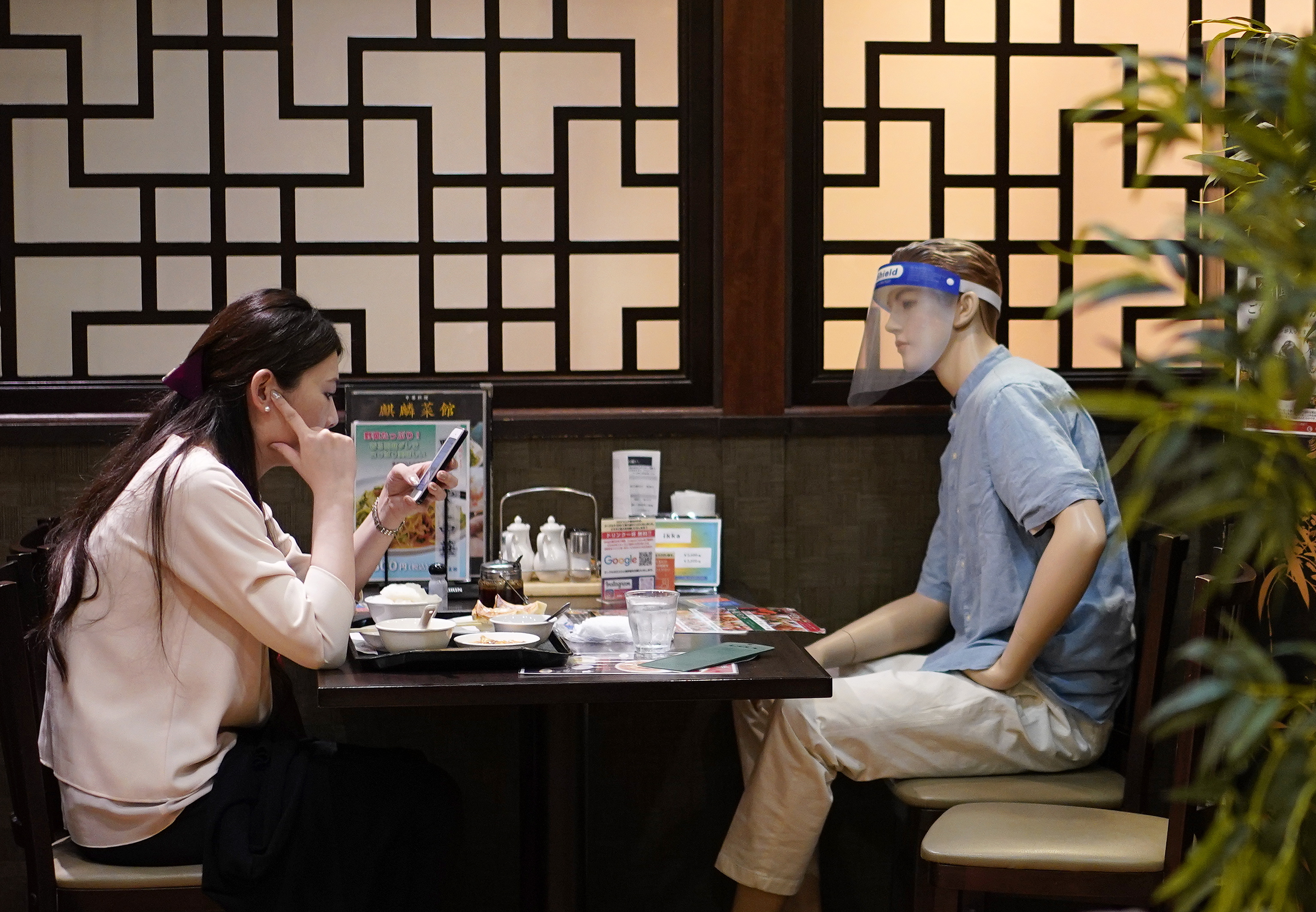A woman sitting across from a mannequin used to enforce social distancing at a restaurant in Tokyo, which recorded 266 cases yesterday.