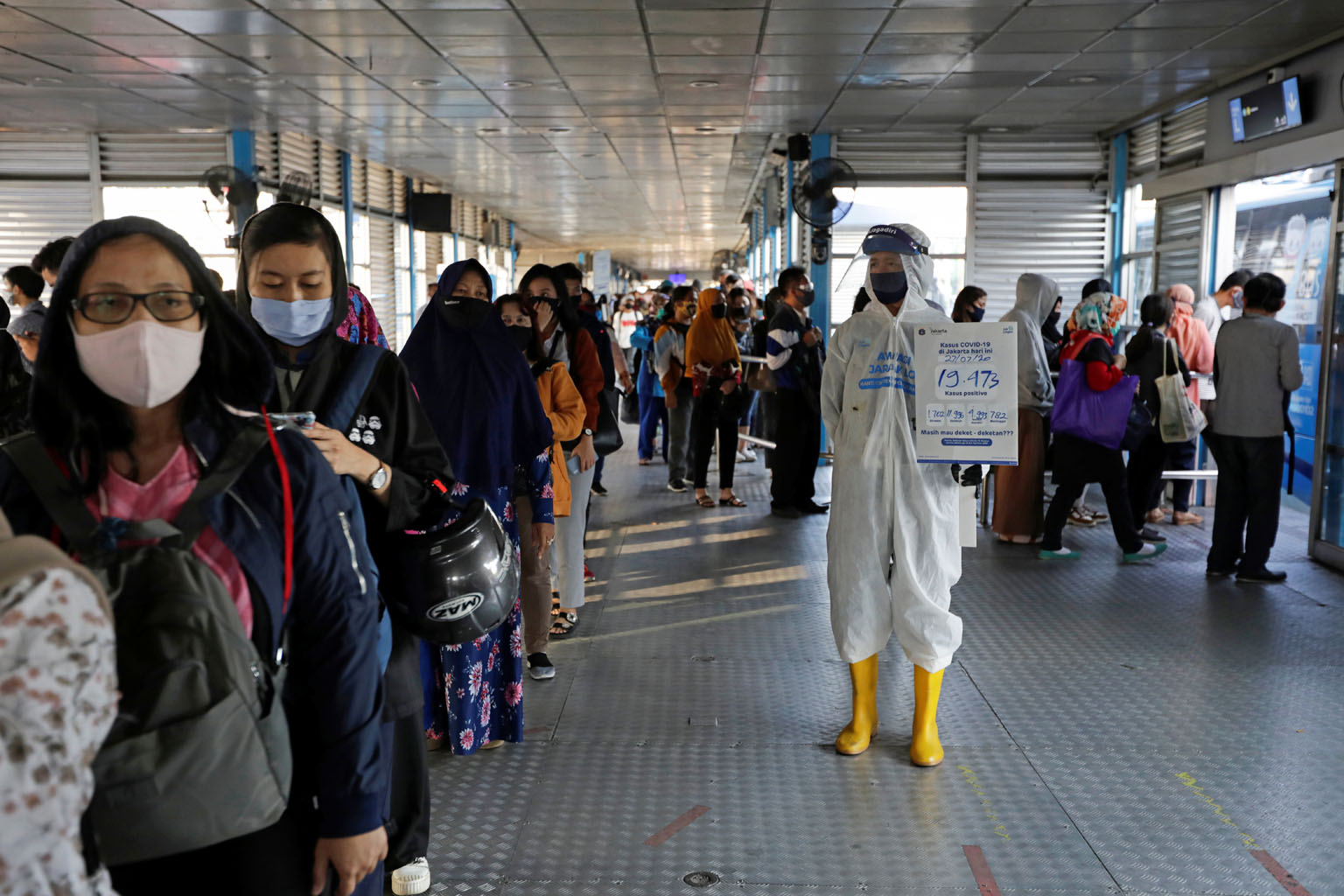 A worker at a central bus hub in Jakarta holding a placard with the total number of positive Covid-19 cases on Monday written on it. Since the middle of the month, some 45 clusters - of two or more simultaneous infections - have emerged as residents