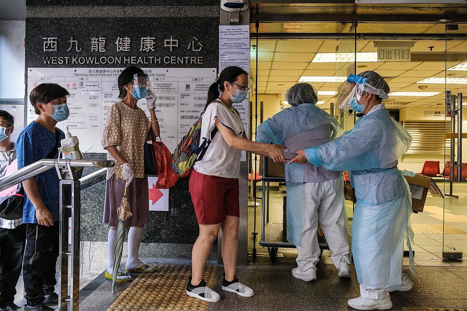 Workers at a government clinic giving out free coronavirus test kits to residents in Hong Kong's Sham Shui Po district early yesterday morning, as part of a citywide testing initiative. Hong Kong's confirmed Covid-19 infections have surpassed the 3,0