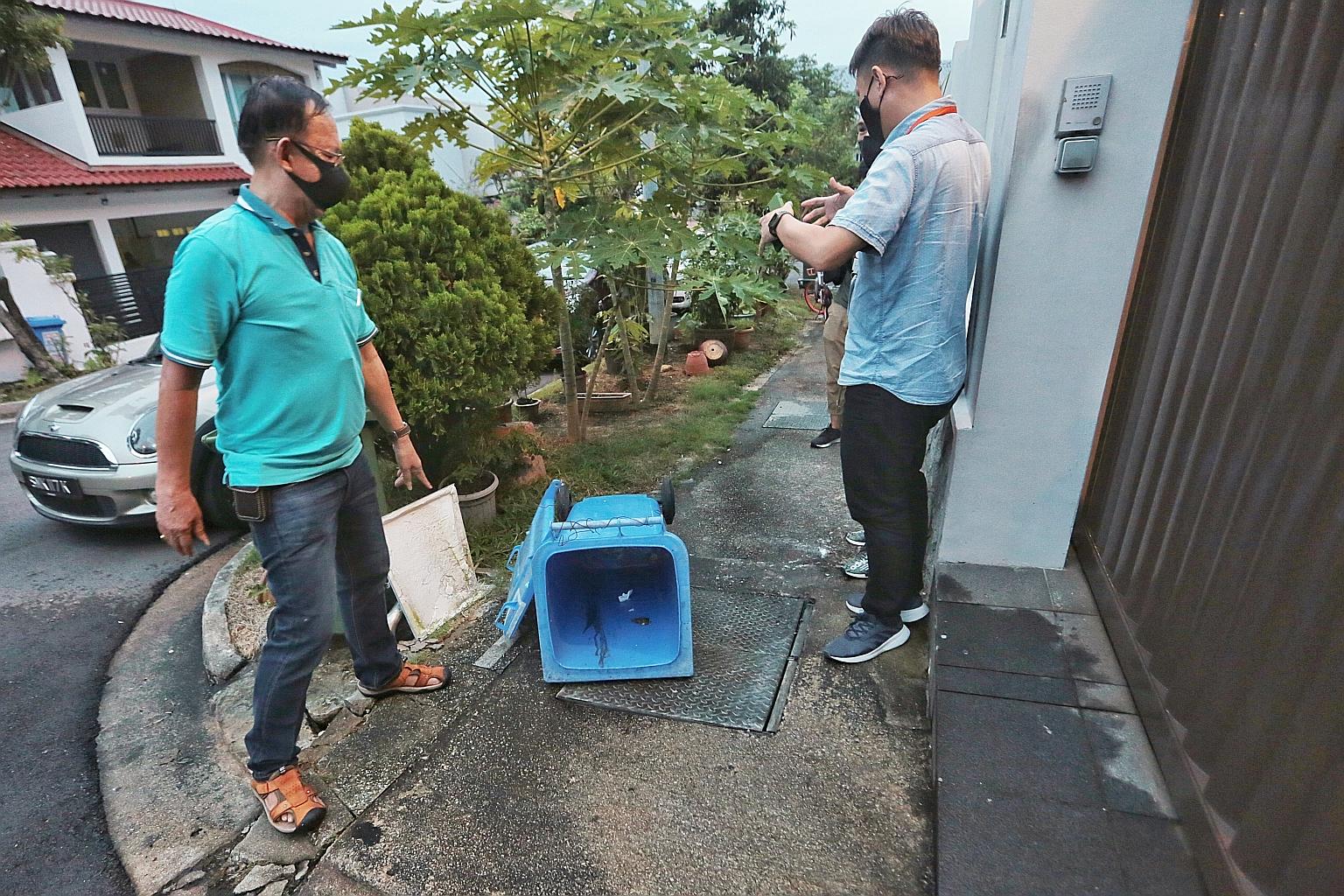 Mr Lew (left), a resident of Tai Keng Gardens, pointing at the bin where he and his family discovered the baby believed to have been abandoned. As soon as Mr Lew lifted the lid, he saw the infant wrapped in a towel and placed in paper bags. The polic