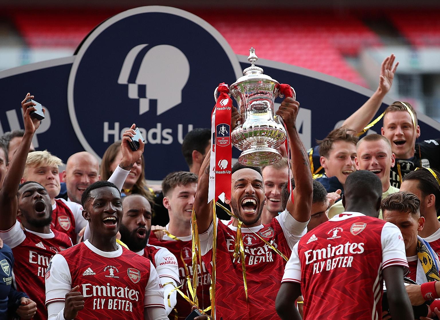 Above: Pierre-Emerick Aubameyang beats Chelsea goalkeeper Willy Caballero to give Arsenal a 2-1 lead at Wembley Stadium, which they held on to win. Left: Gabonese striker and captain Aubameyang holding the trophy as the Gunners celebrate their record