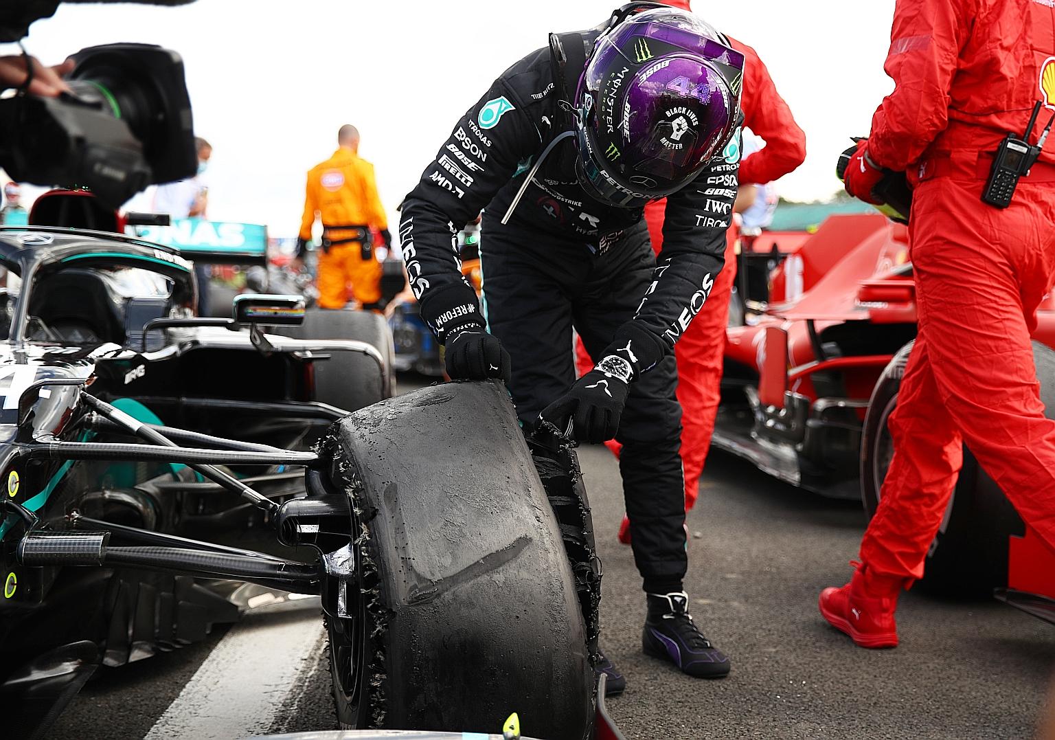 Lewis Hamilton checking his Mercedes car's front left tyre after hanging on to win the British Grand Prix for a seventh time at Silverstone yesterday despite a puncture on the final lap.