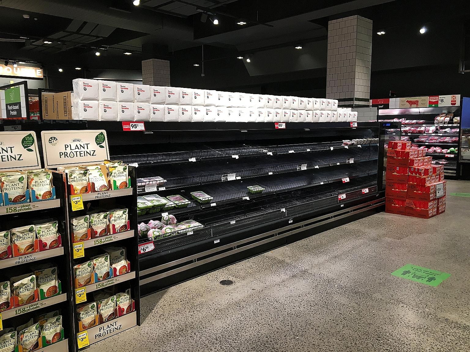 Empty shelves in the poultry section of a Woolworths supermarket (above), and police officers and soldiers patrolling the Treasury Gardens (right) in Melbourne yesterday, as Australia's second-biggest city hunkered down under a strict curfew from 8pm