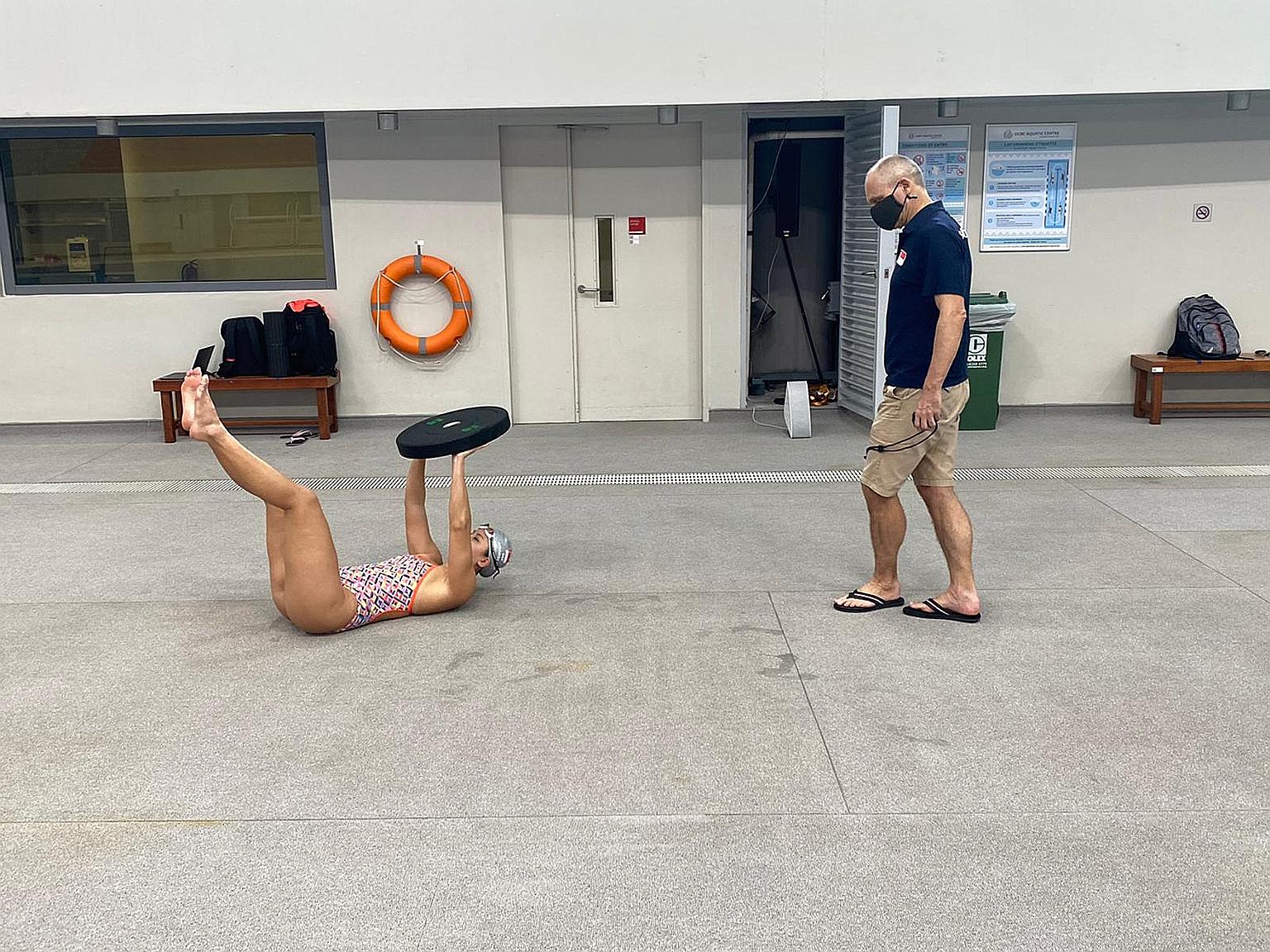 National swimming coach Stephan Widmer, his mask on, keeps the appropriate social distance as he monitors the progress of Amanda Lim at the OCBC Aquatic Centre.
