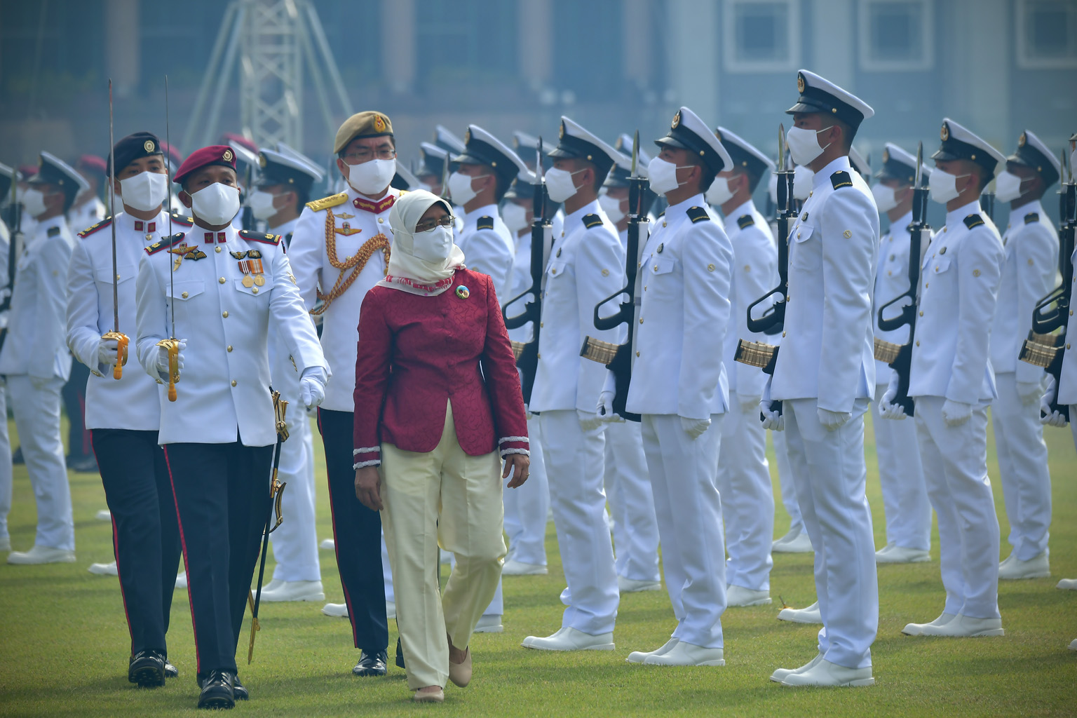 President Halimah Yacob inspecting the guard of honour at the Padang yesterday morning. Her silk cotton scarf and enamel brooch bore designs by two visually impaired artists.