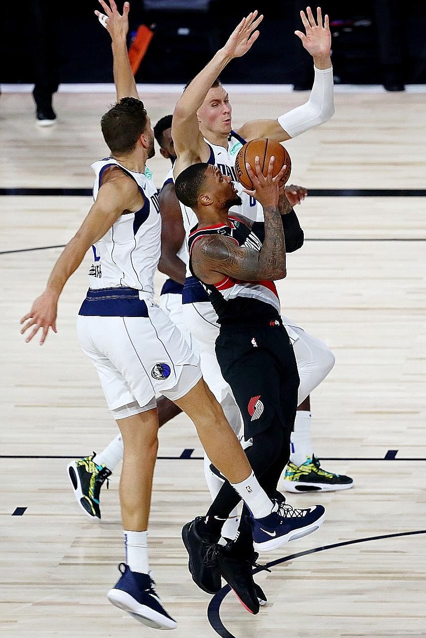 Portland guard Damian Lillard going for a shot despite the close attention of Dallas forward Maxi Kleber (left) and other players. The Blazers won 134-131.