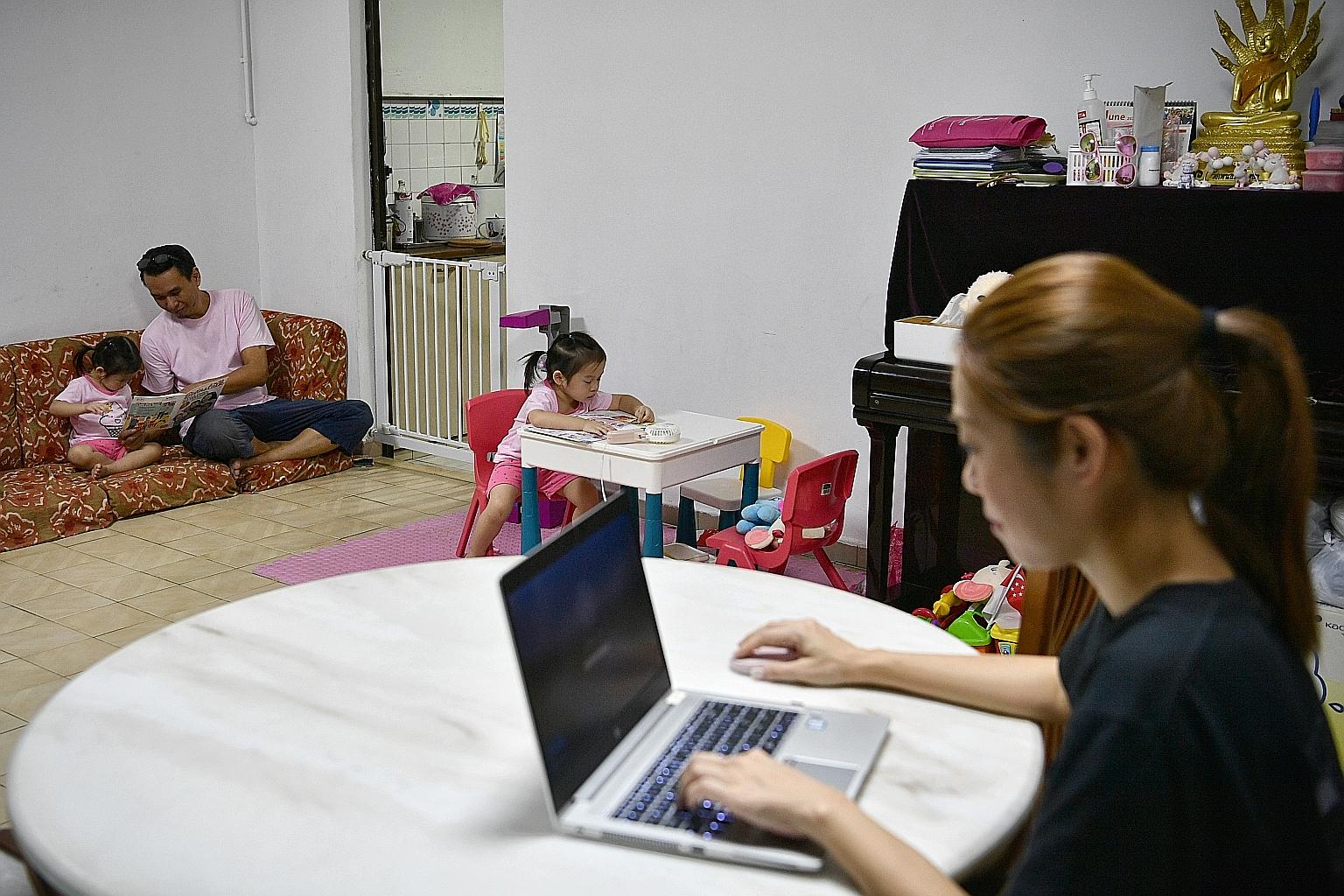 Office manager Joyce Poh, 41, trying to work on the dining table, while her husband David Lee, 46, a private-hire driver, read to 21/2-year-old daughter Amanda, and twin Belinda was engaged in a book last Thursday. ST PHOTO: ARIFFIN JAMAR