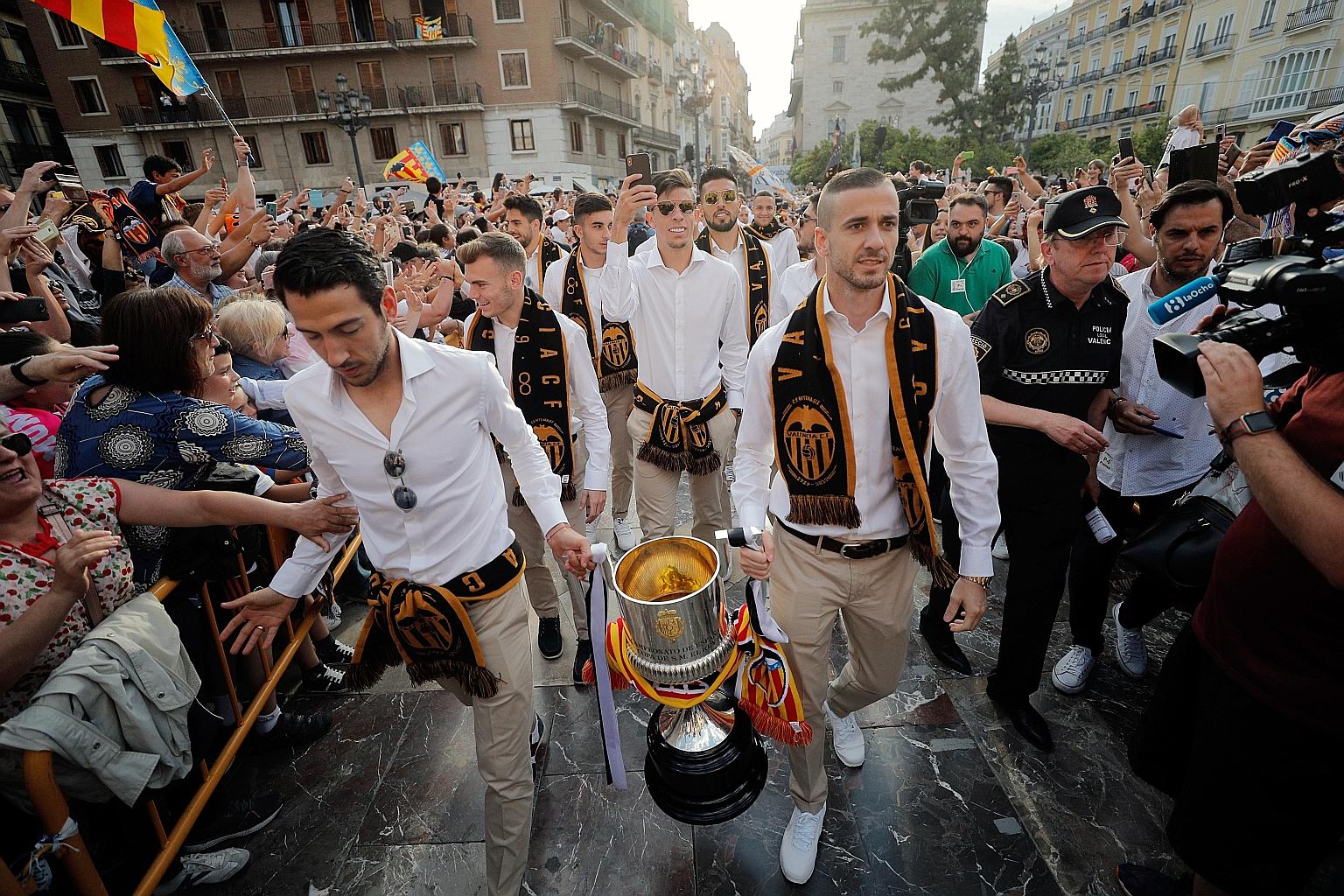 Above: Dani Parejo, Valencia's former captain who was sold to Villarreal, and Jaume Domenech carrying the Spanish King's Cup - the club's first trophy in 11 years - during celebrations in May last year. Below: Ferran Torres, taking on Real Madrid's F