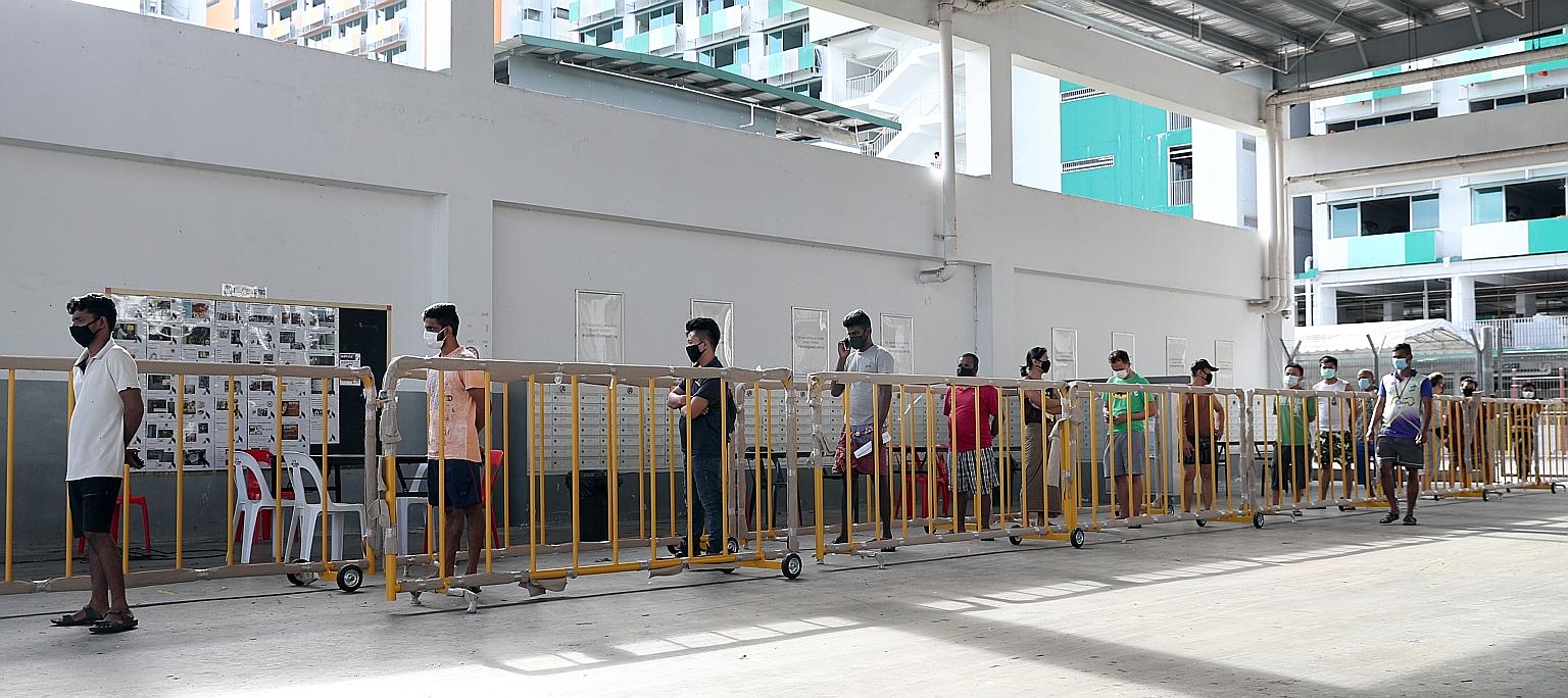 Migrant workers queueing to receive SIM cards at a dormitory cleared of Covid-19 earlier this month. There are currently about 18,600 workers overall who are still serving quarantine.