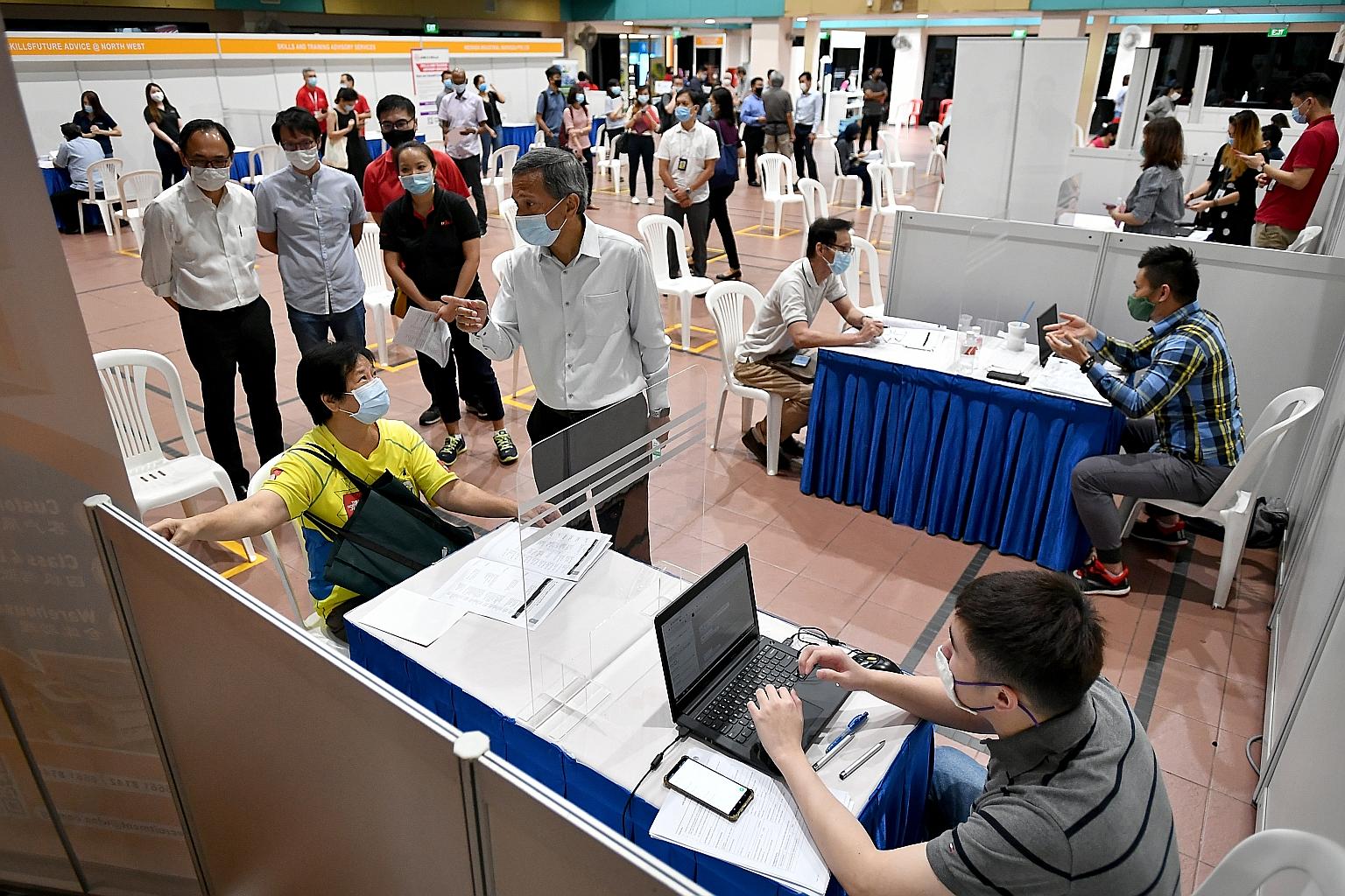Foreign Minister Vivian Balakrishnan speaking to a job seeker yesterday at a job fair held by e2i at Bukit Panjang Community Club. Also at the event were Bukit Panjang MP Liang Eng Hwa (standing, left) and Holland-Bukit Timah GRC MP Edward Chia (stan