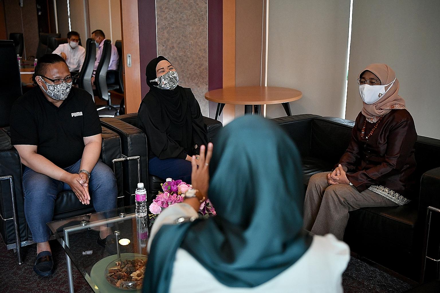 President Halimah Yacob interacting with lorry crane operator Mohammad Faizal Abdul Kadir, 37, and his wife, admin assistant Zareeda Mosah, 36, at AMP Singapore's office at Pasir Ris East Community Building yesterday. ST PHOTO: LIM YAOHUI