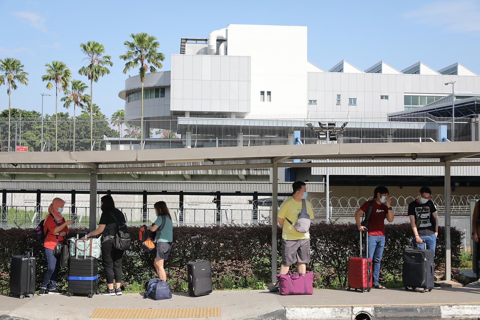 Workers employed at a factory in Kallang, who arrived in Singapore from Malaysia on Monday, waiting for their bus transport at the Woodlands Train Checkpoint to take them to their quarantine facility where they must stay for seven days. Under the per