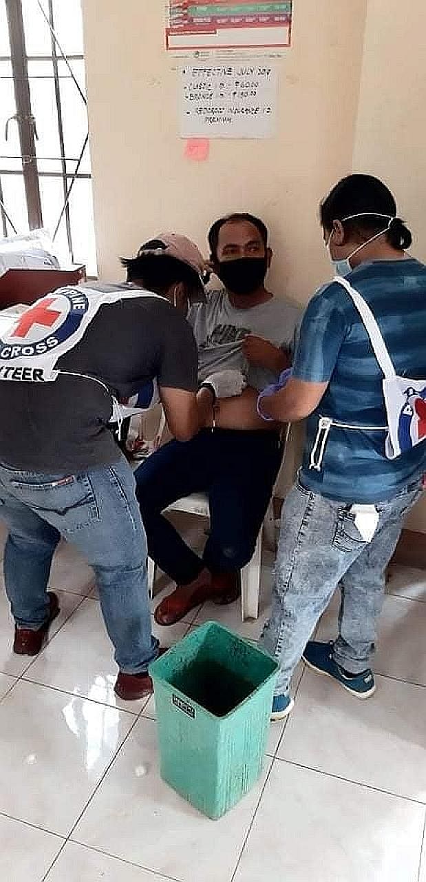 Volunteers attending to an injured man after the explosions in Jolo yesterday. Major-General Corleto Vinluan, chief of the Western Mindanao Command, said the attacks could be the work of the same faction of the Abu Sayyaf extremist group that was beh