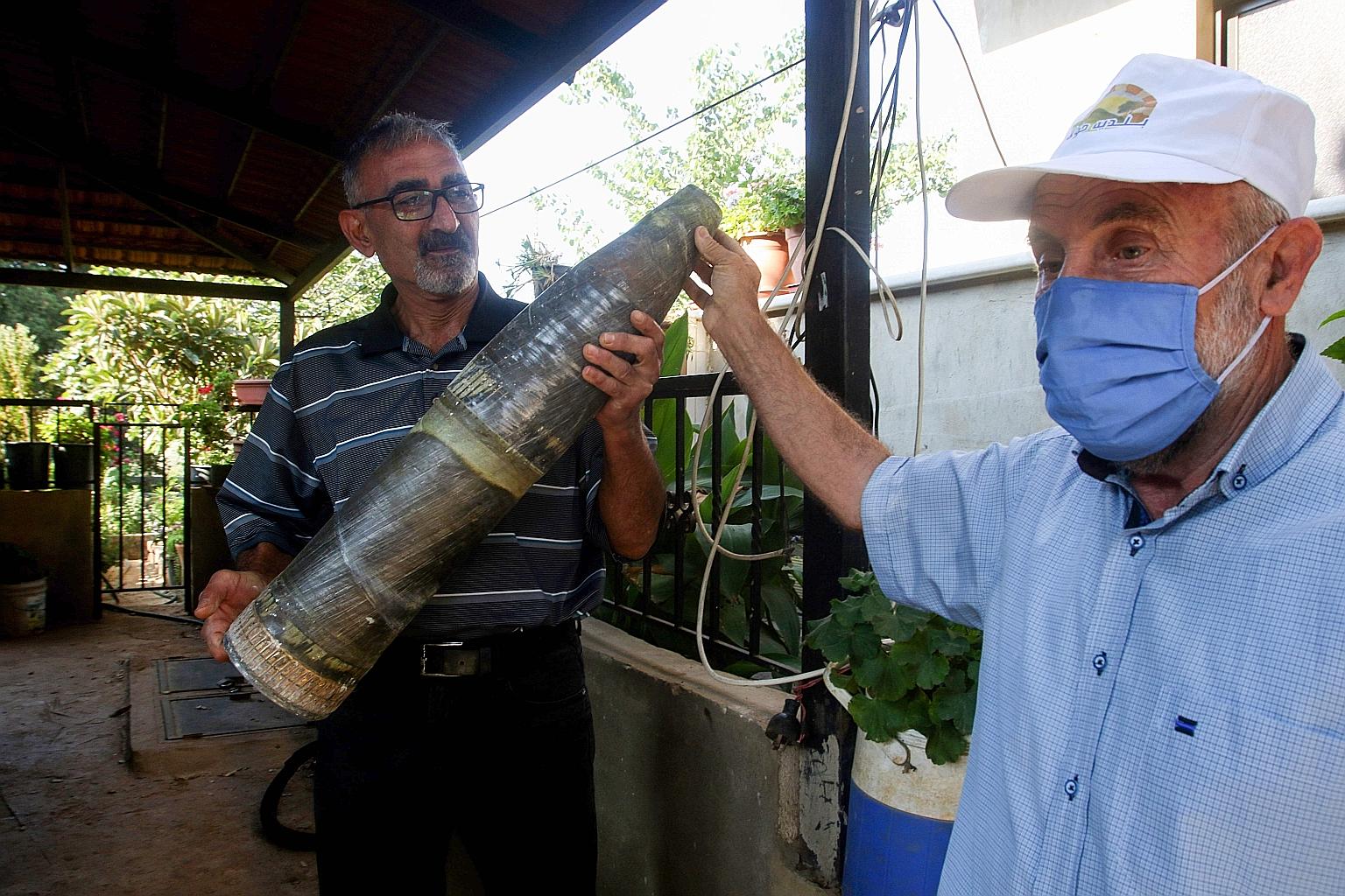 Lebanese men in Houla village with an unexploded projectile allegedly fired by Israeli soldiers on Tuesday. Israel said yesterday that it had launched air strikes against Hizbollah observation posts in Lebanon after shots were fired from across the b