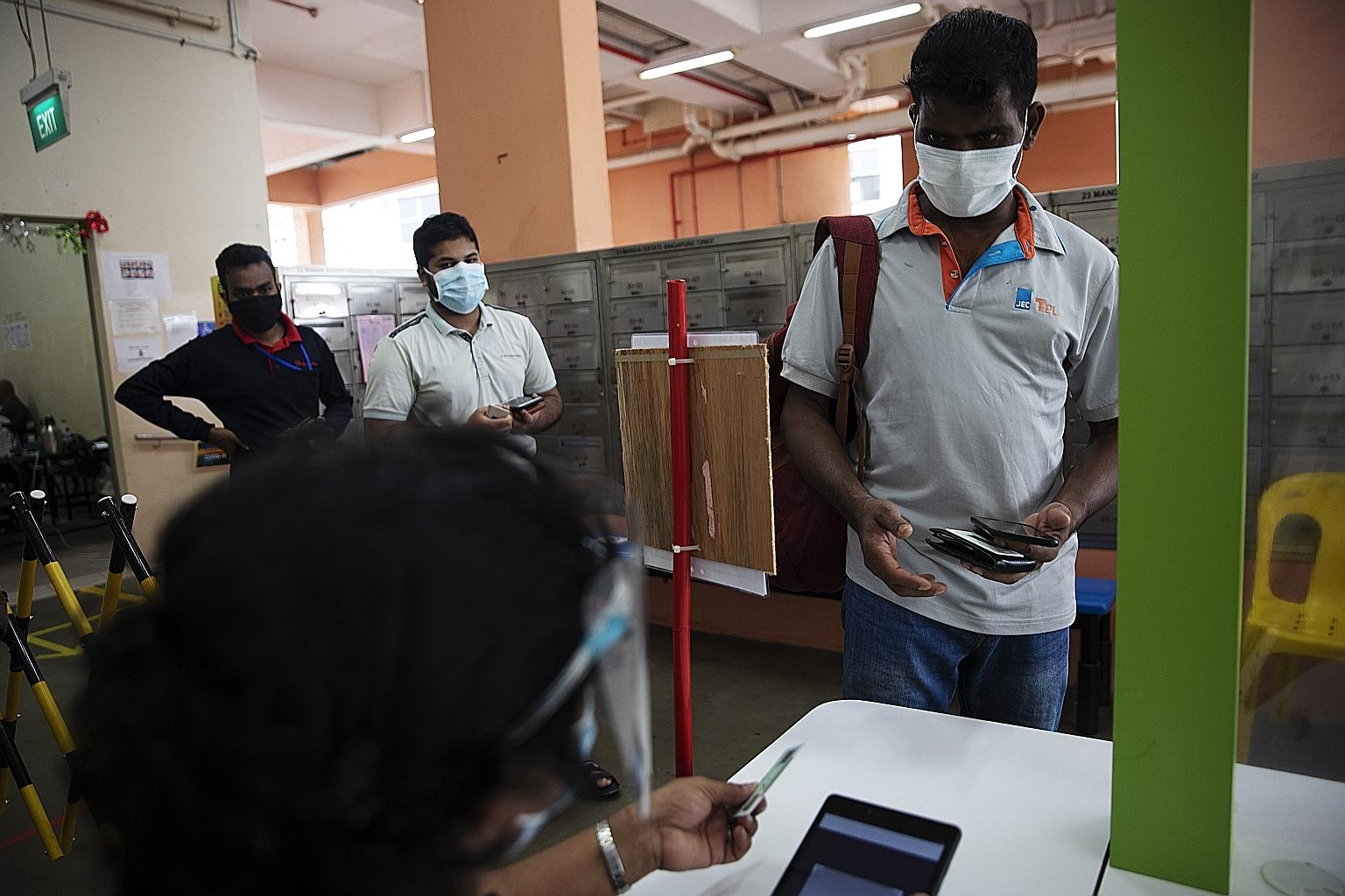 Migrant workers showing their ID cards and green AccessCode as they leave for work at Westlite Juniper dormitory. The green AccessCode indicates that the workers have fulfilled several requirements, including that they have tested negative for Covid-