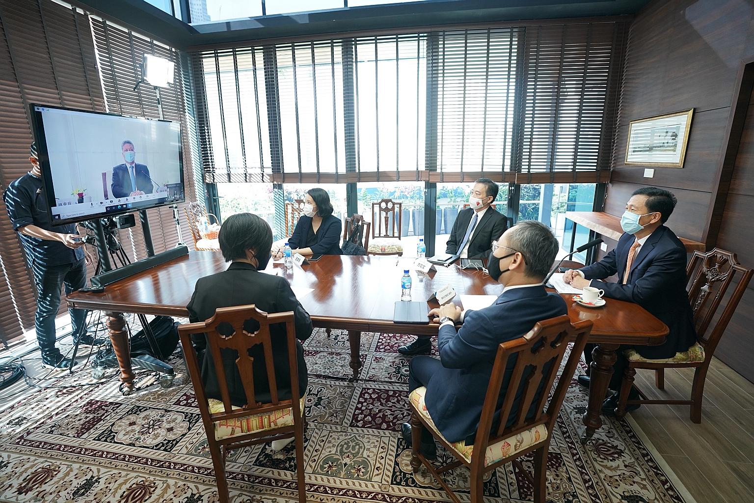 Guangdong Governor Ma Xingrui (on screen) with Singapore Transport Minister Ong Ye Kung (right), Enterprise Singapore chief executive Png Cheong Boon (on Mr Ong's right) and delegates from Enterprise Singapore and the Ministry of Trade and Industry a