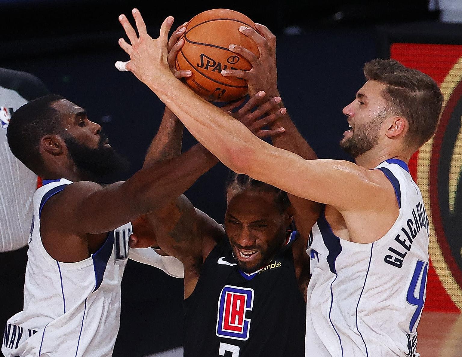 Clippers forward Kawhi Leonard driving between the Mavericks' Tim Hardaway Jr and Maxi Kleber during Game 6 of their Western Conference first-round series.