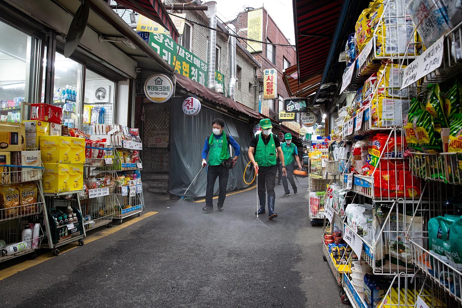Workers spraying disinfectant to curb the spread of Covid-19 in Seoul on Wednesday. PHOTO: EPA-EFE