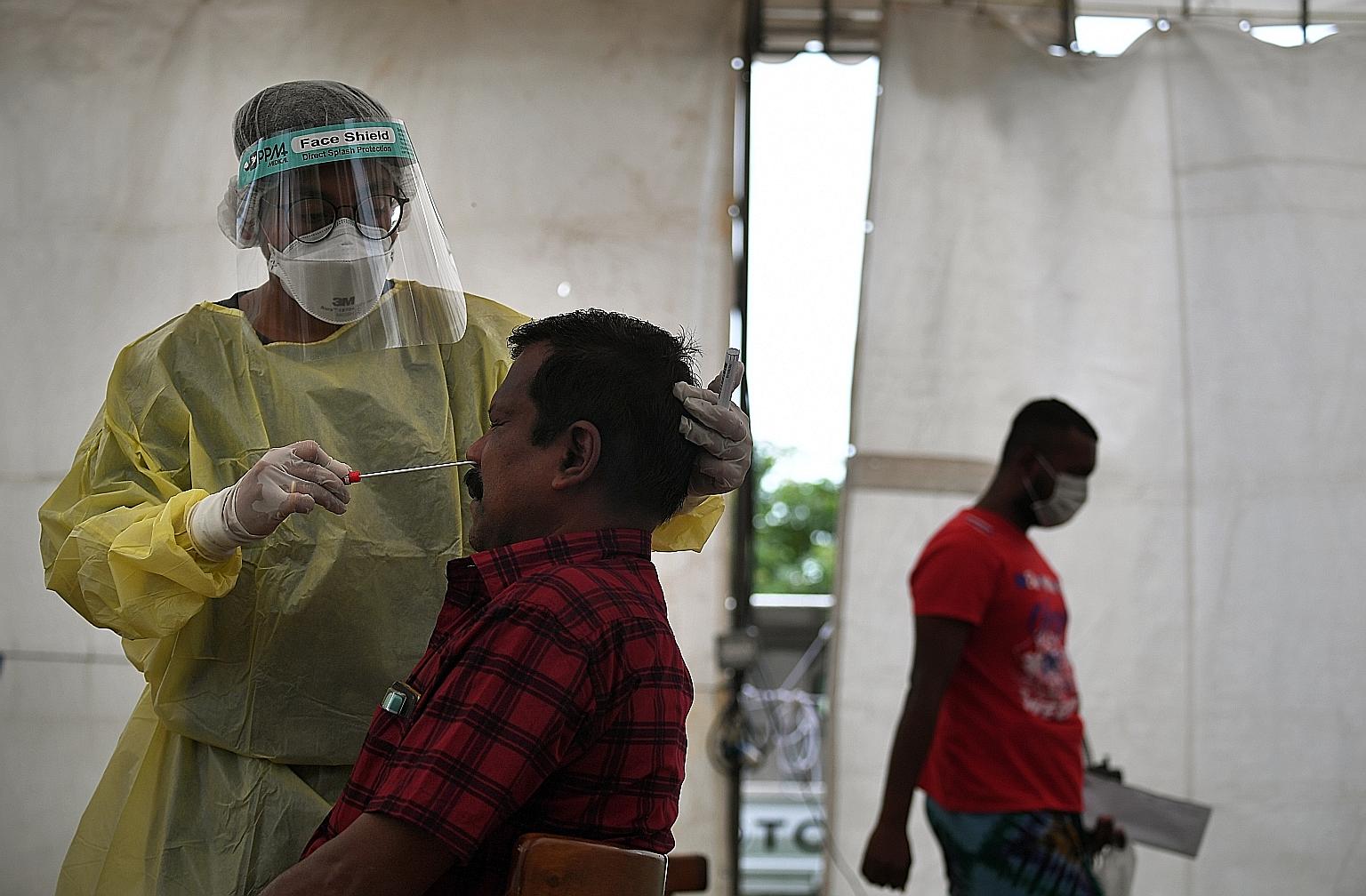 A foreign worker undergoing a swab test in June. Regular testing is one of several measures introduced to allow the safe restart of work. Others include implementing safe living measures in dorms and arranging staggered pick-up and drop-off timings t