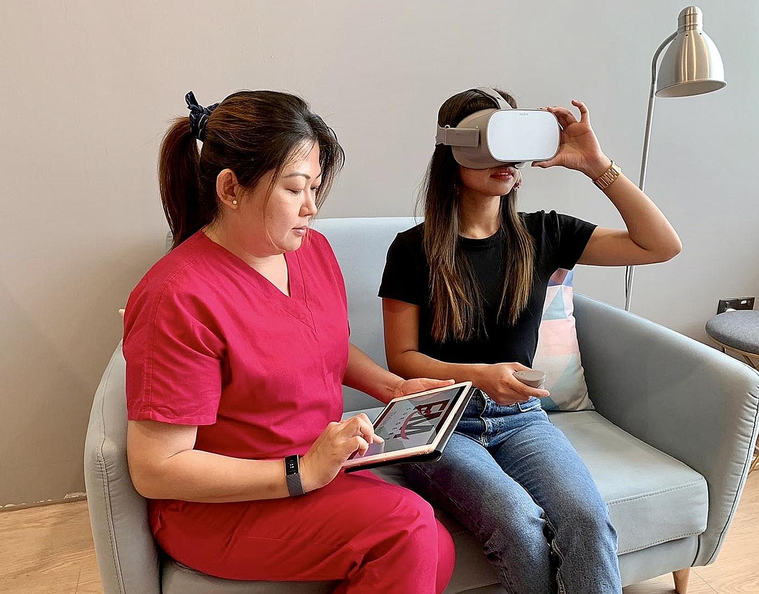 Nurse Chong Pei San with a patient who is watching a virtual-reality video on breast wide excision and sentinel lymph node biopsy through a headset.