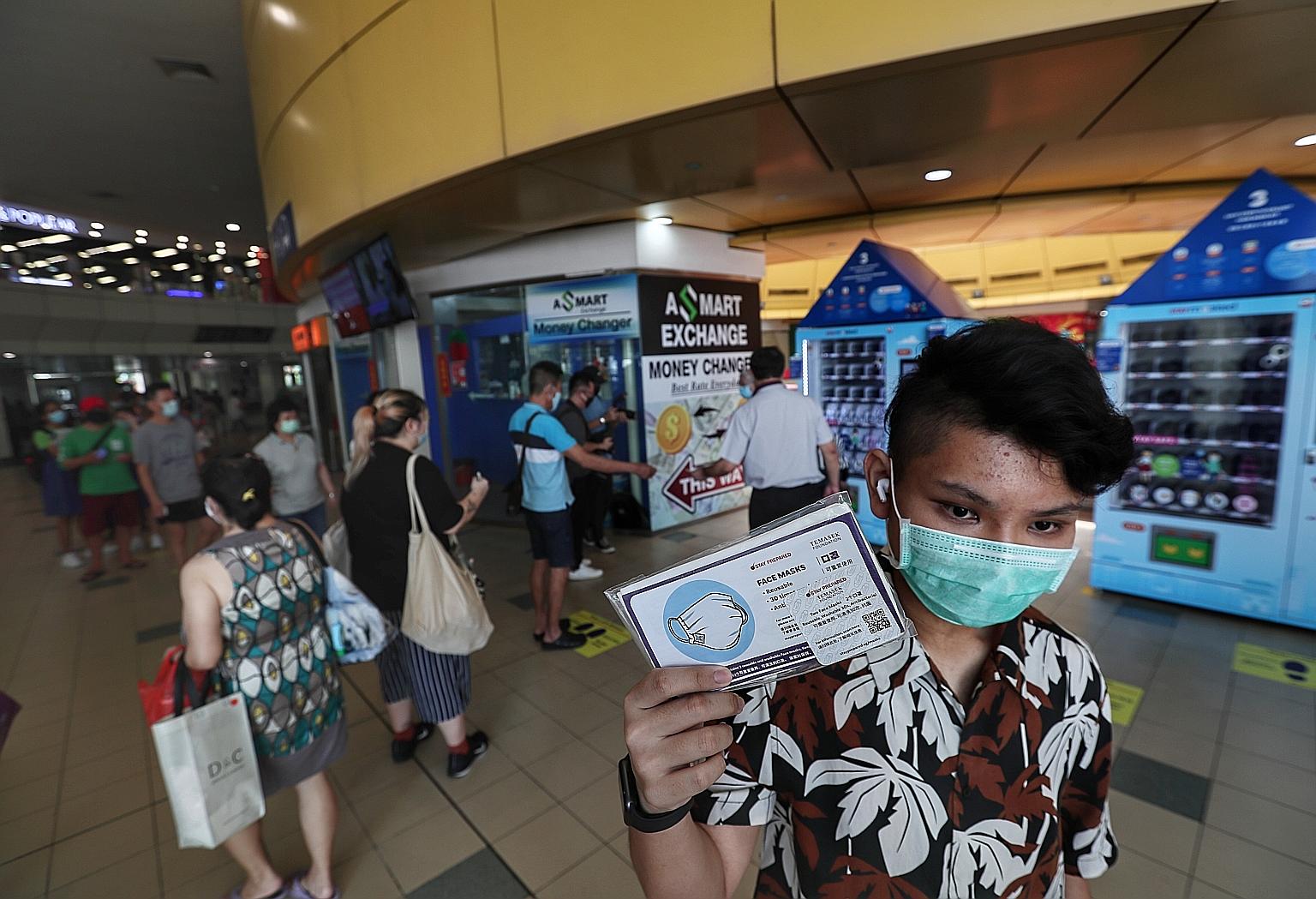 Thai national Pirapat, 17, a student in Singapore, with a free reusable mask from Temasek Foundation collected from a vending machine at the Toa Payoh bus interchange in June. A total of 11 million masks were given out to residents here. ST PHOTO: KE