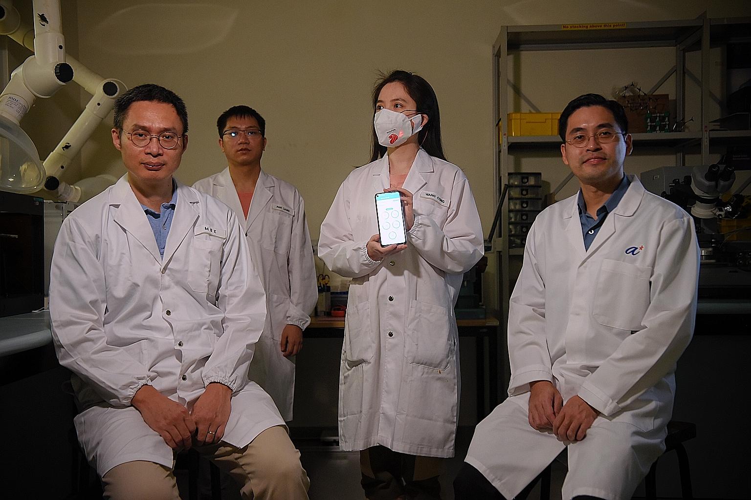 The team behind the smart mask system - (from far left) Professor Chen Xiaodong, research fellows Liang Pan and Wang Cong, and Professor Loh Xian Jun. Ms Wang is wearing the smart mask, which allows the wearer's real-time health data to be transmitte