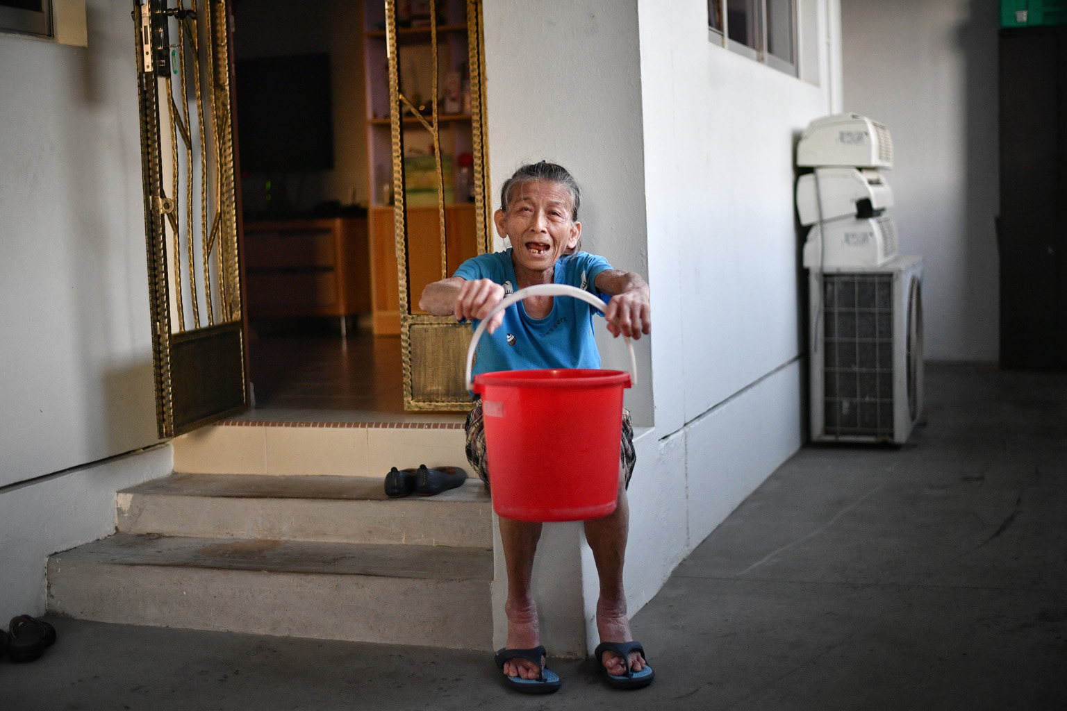 Madam Lim Ee Chin with the pail she used to help put out the fire on Aug 9. She cannot recall how many pails of water she fetched that night, but "it felt like an hour that would never end".