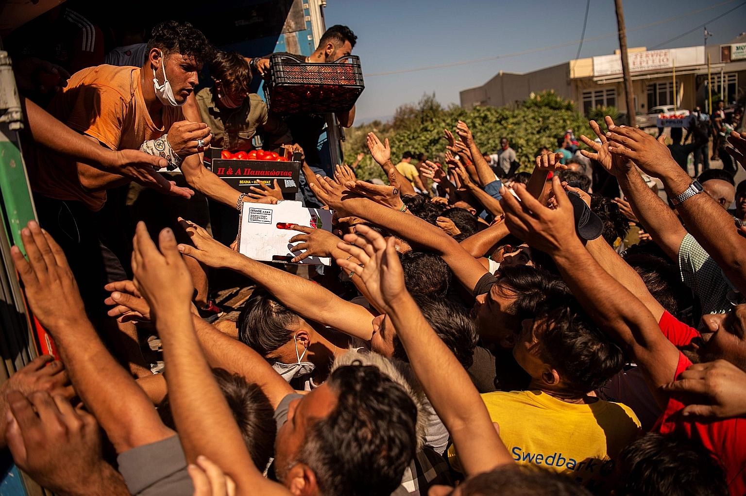 Migrants scrambling for food at a distribution point on Thursday after fires burned Greece's biggest refugee camp, Moria, to the ground. PHOTO: AGENCE FRANCE-PRESSE