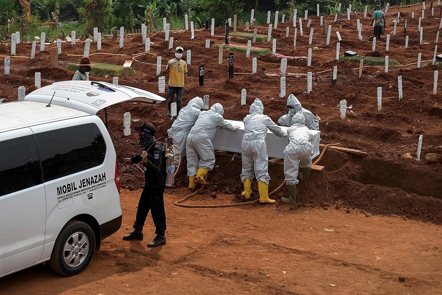 Workers in protective gear burying a Covid-19 victim at a site earmarked for pandemic cases in Jakarta yesterday. Indonesia moved to enforce mask wearing across the country as infections rose by 3,737 to 210,940 yesterday, and 88 more deaths were rec