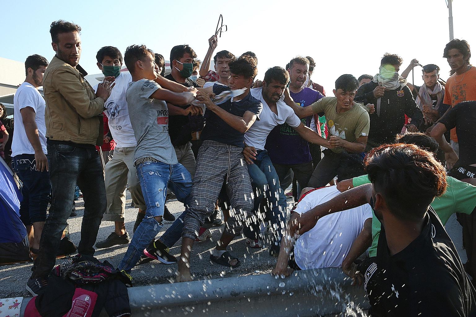 Asylum seekers tussling over a mobile charger near the razed Moria refugee camp in Greece on Wednesday. The camp, with its poor living conditions, had hosted more than 12,000 migrants, four times its stated capacity.