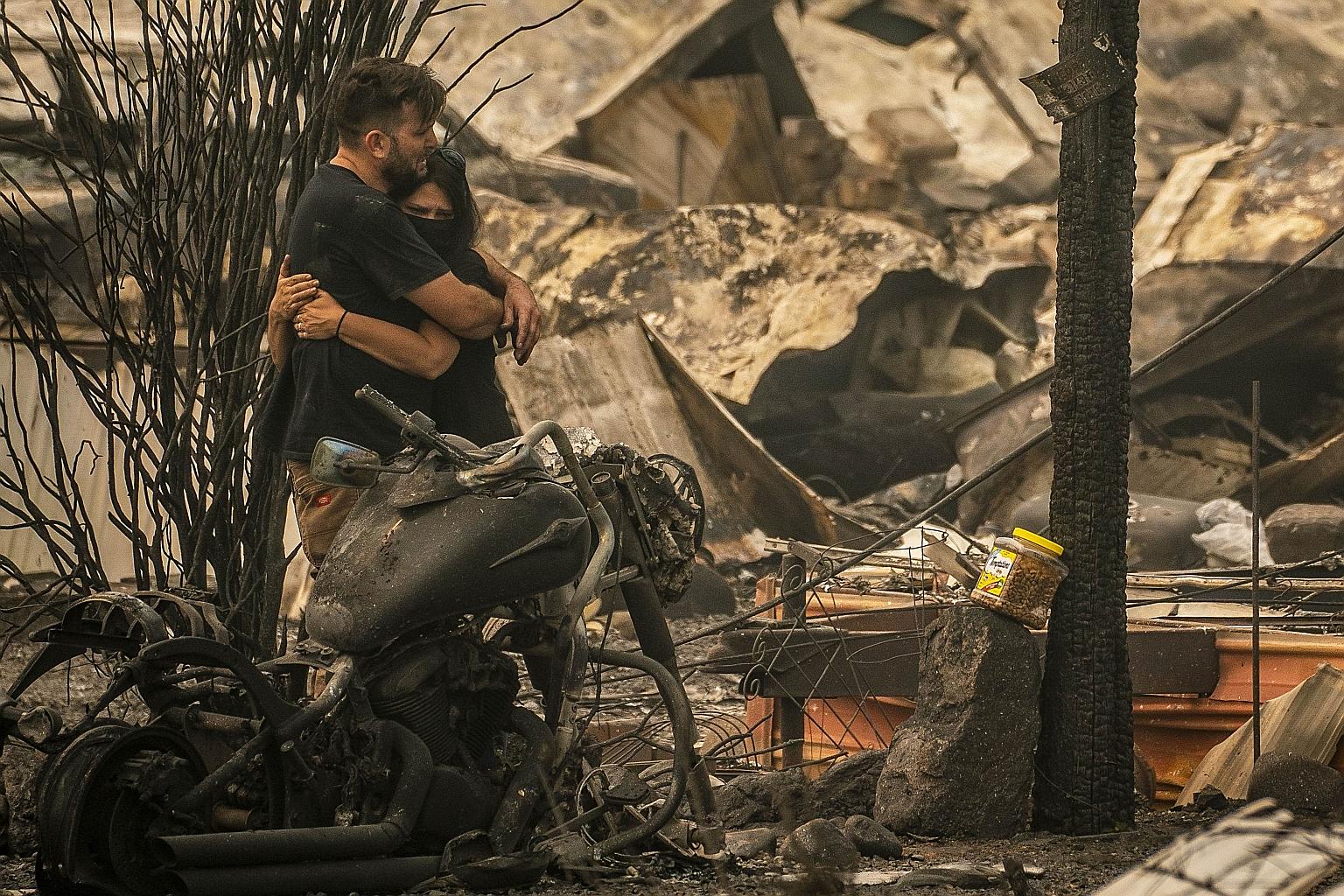 A couple in distress after an unsuccessful search on Friday for their missing cat amid the charred debris of where their home once stood, in a mobile home park in Ashland, Oregon.