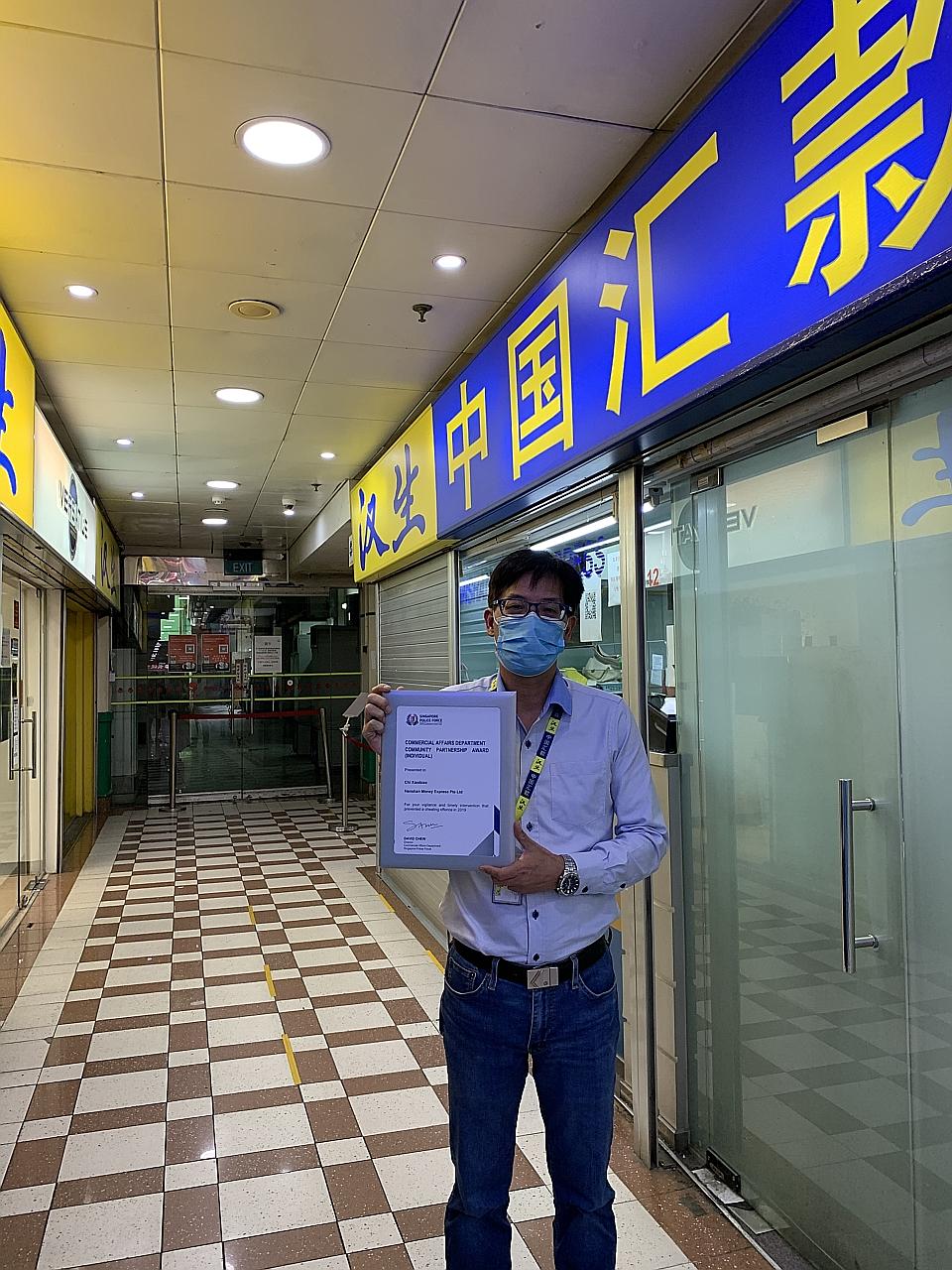 Mr Chi Xiao Biao, a counter staff member at Hanshan Money Express Remittance, with his Community Partnership Award. He was one of 108 individuals and 15 organisations lauded by the Commercial Affairs Department for their contributions to detecting an