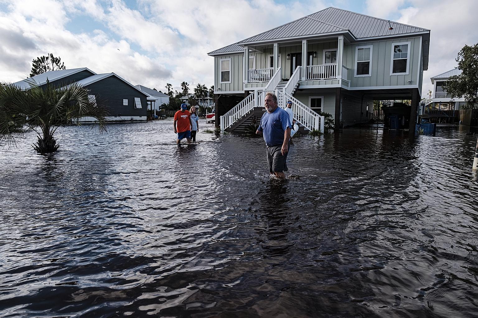 Residents trudging through knee-deep water outside their homes in a flooded neighbourhood in Orange Beach, Alabama, in the United States on Wednesday. Hurricane Sally made landfall early on Wednesday near Gulf Shores, Alabama, as a Category 2 storm o